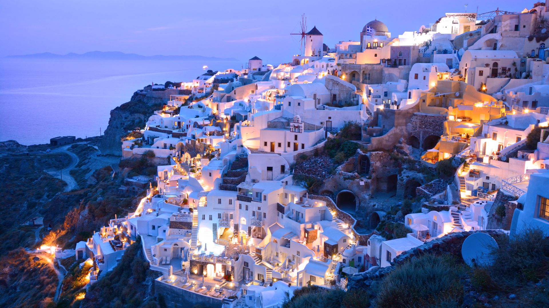 A picturesque view of the white-washed buildings in Santorini, Greece, at dusk.