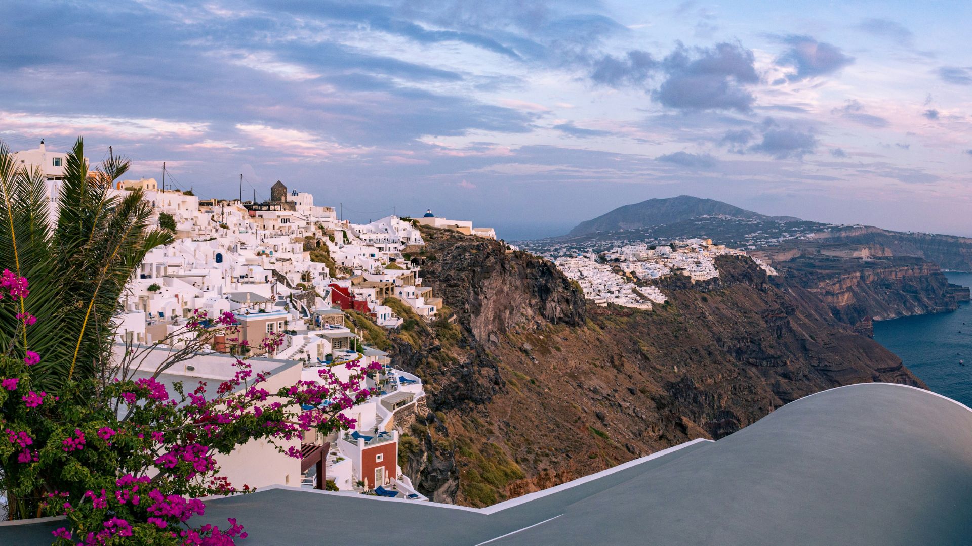 Panoramic view of Oia village in Santorini, with whitewashed buildings and a volcanic caldera.
