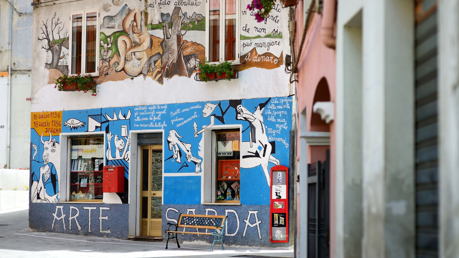 A building in Orgosolo, Sardinia, Italy, is adorned with murals and the text "ARTE SADA."