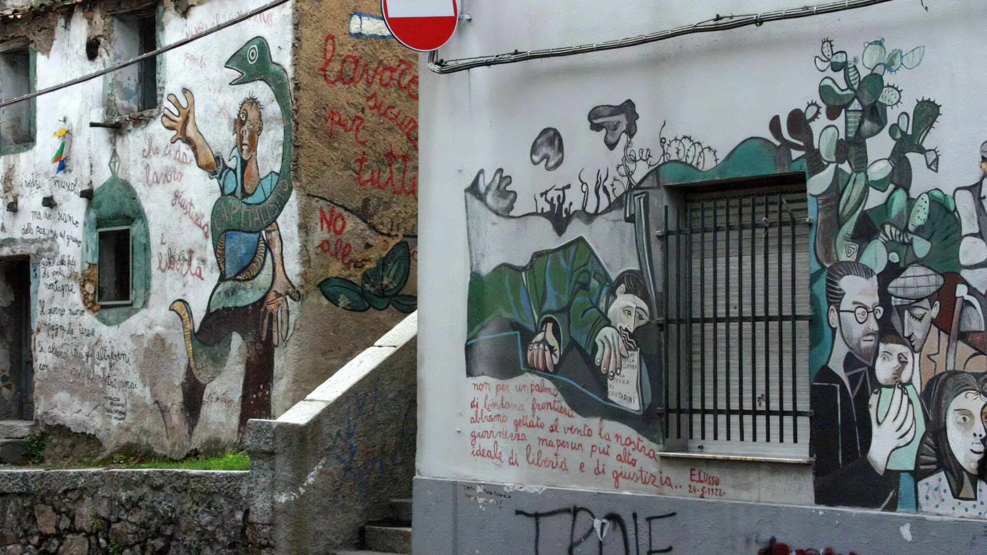 A street in Orgosolo, Sardinia, features murals on buildings.