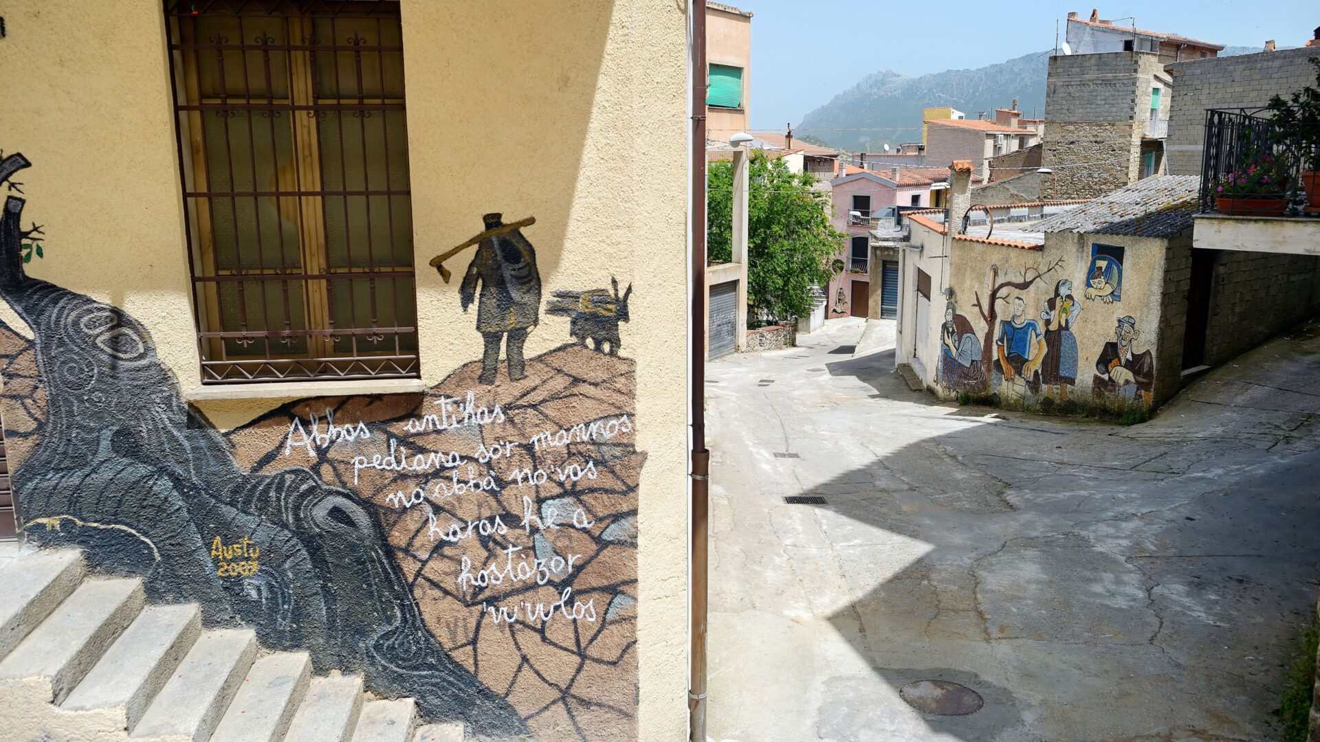 A street in Orgosolo, Sardinia, features murals on buildings.