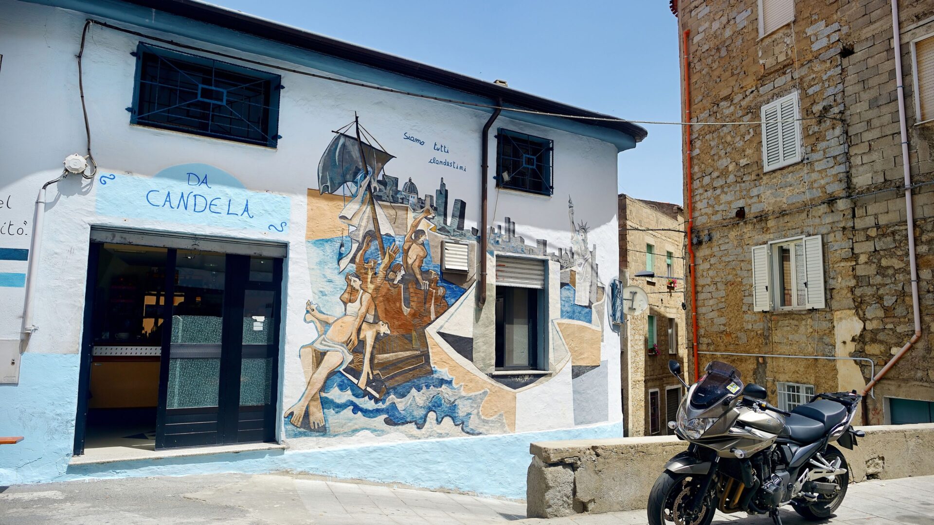 A street in Orgosolo, Sardinia, features murals on buildings.