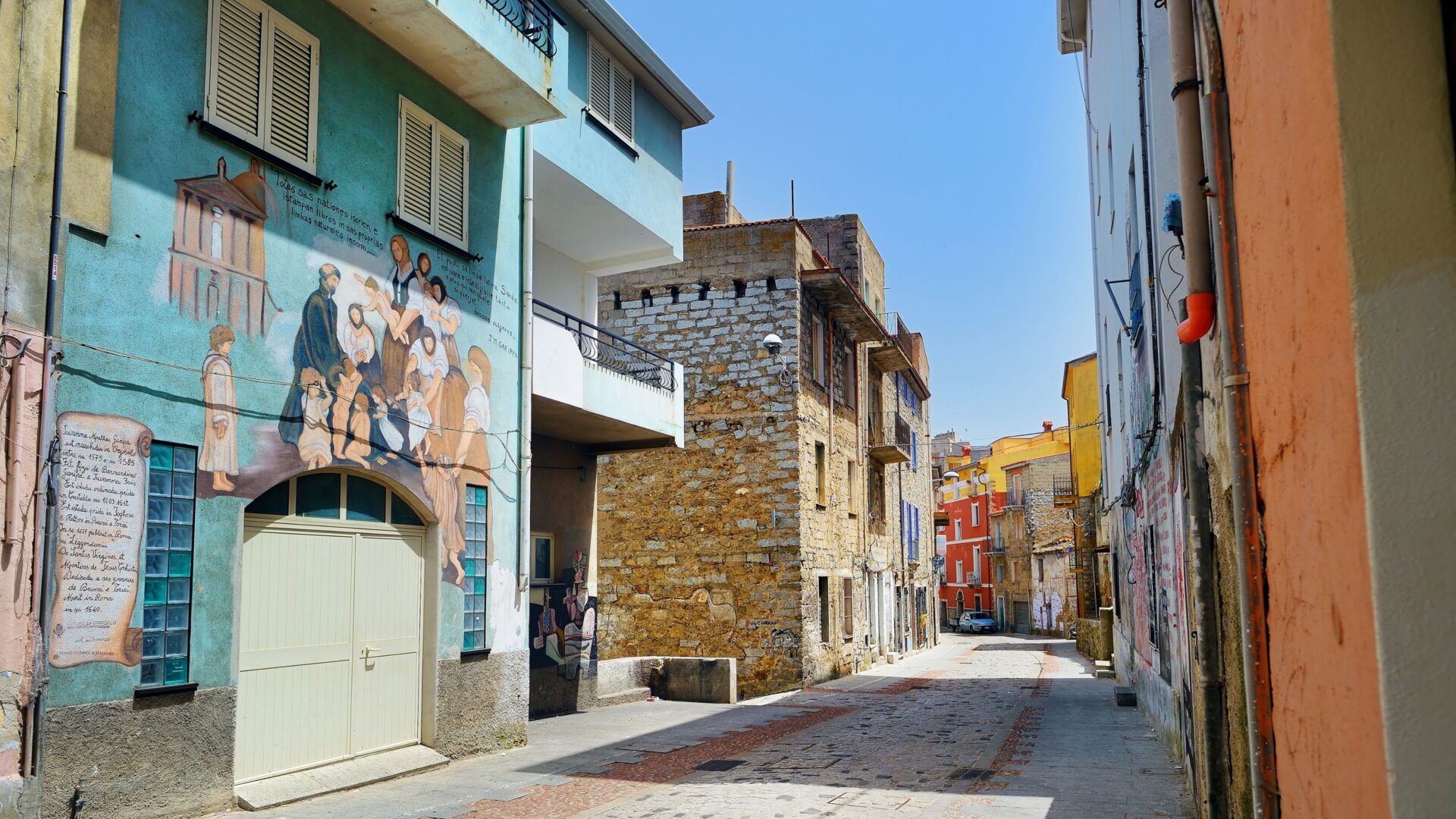 A street in Orgosolo, Sardinia, features murals on buildings.