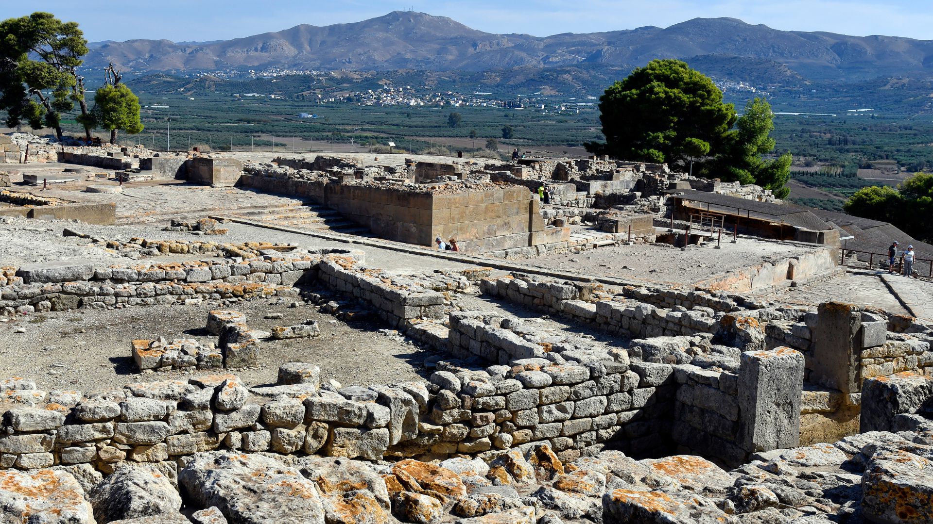 Ruins of the ancient Minoan palace of Phaistos on a hillside in Crete, featuring stone walls and remnants of structures.