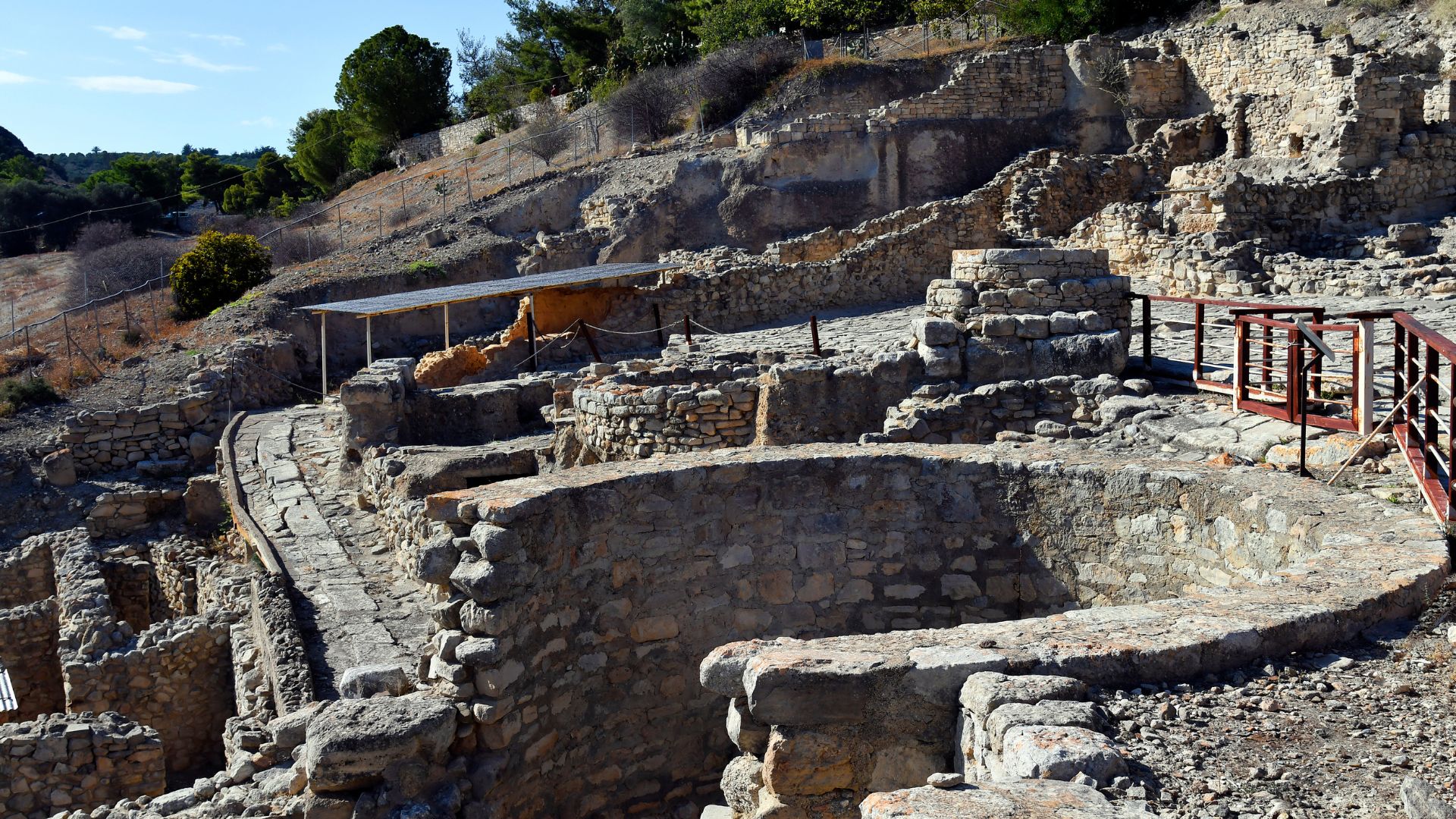 Ruins of the ancient Minoan palace of Phaistos on a hillside in Crete, featuring stone walls and remnants of structures.