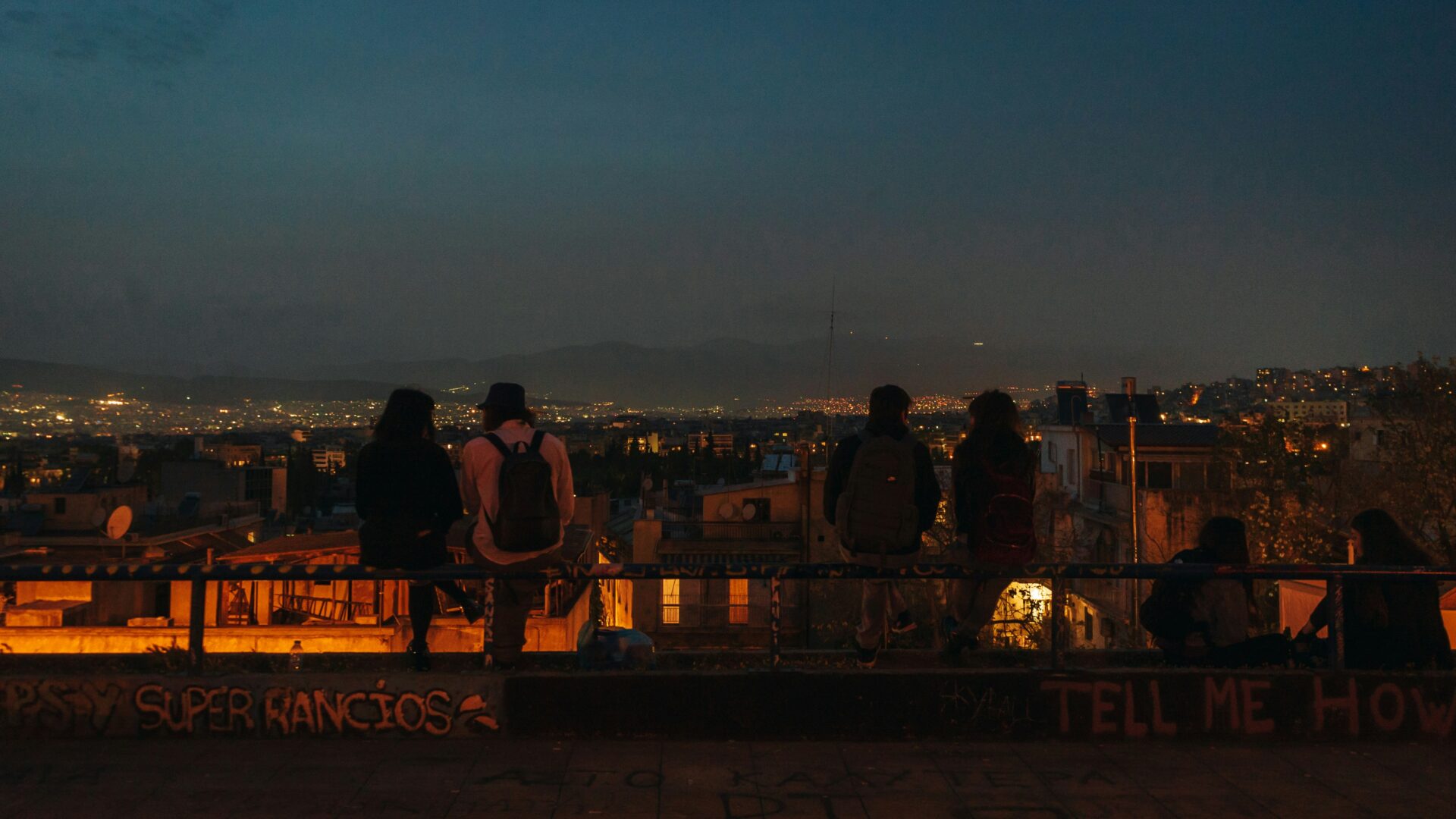 People at a rooftop rail in Athens