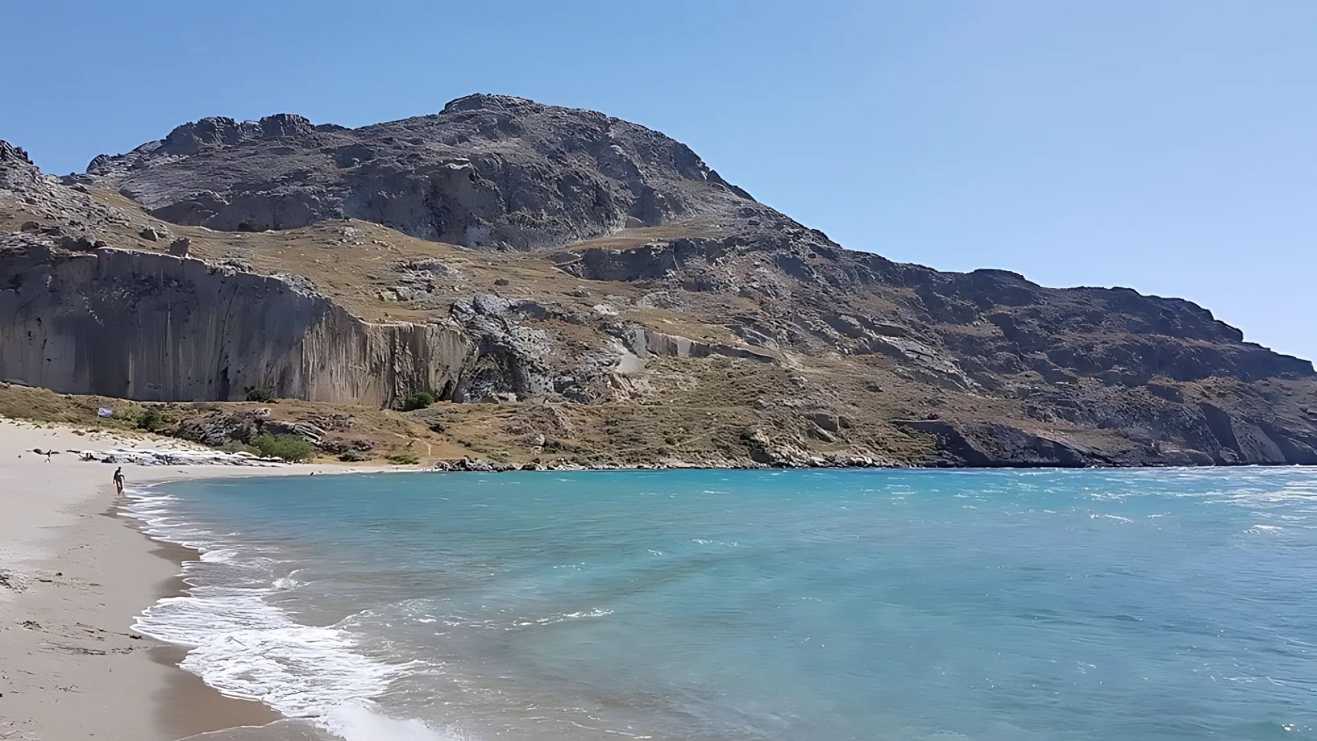 Plakias beach in Crete features its long sandy shoreline bordered by the turquoise waters of the sea and rugged hills.