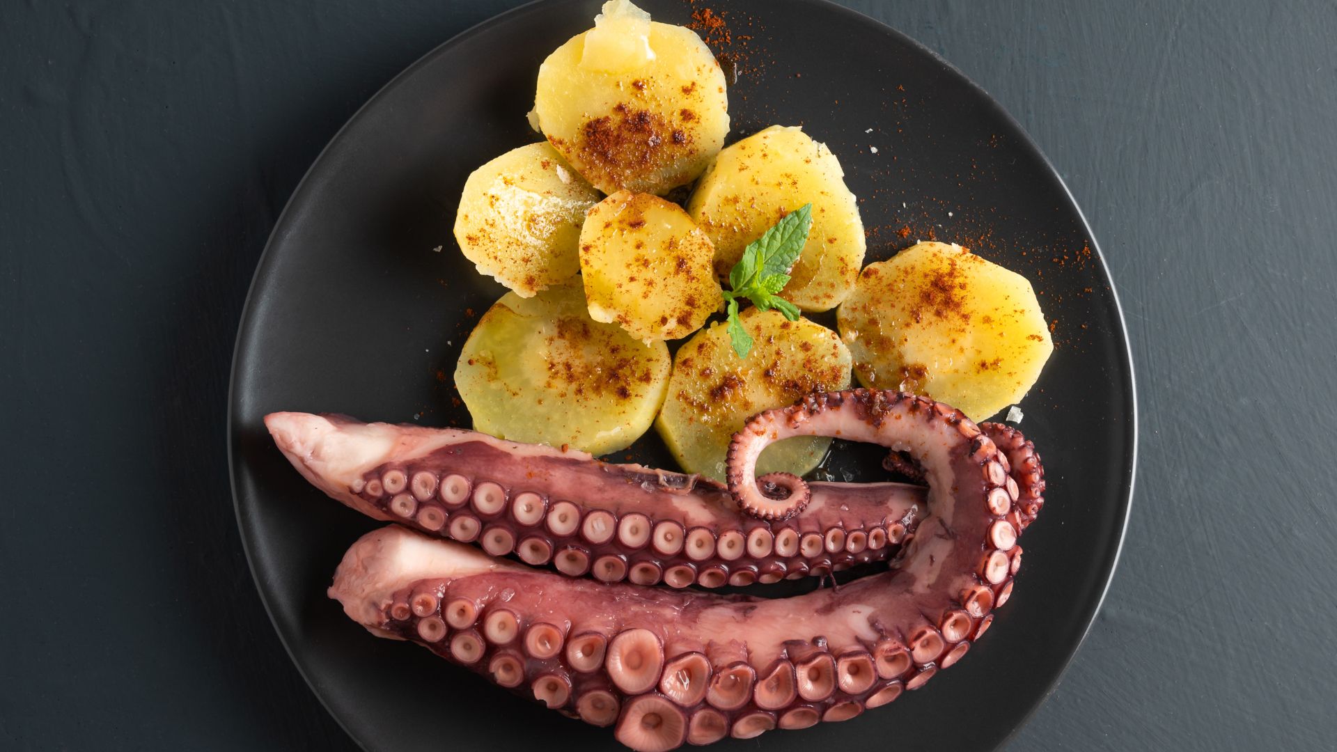 Polpo con Patate on a plate consists of boiled or braised octopus and potatoes, dressed with olive oil, lemon juice, and herbs
