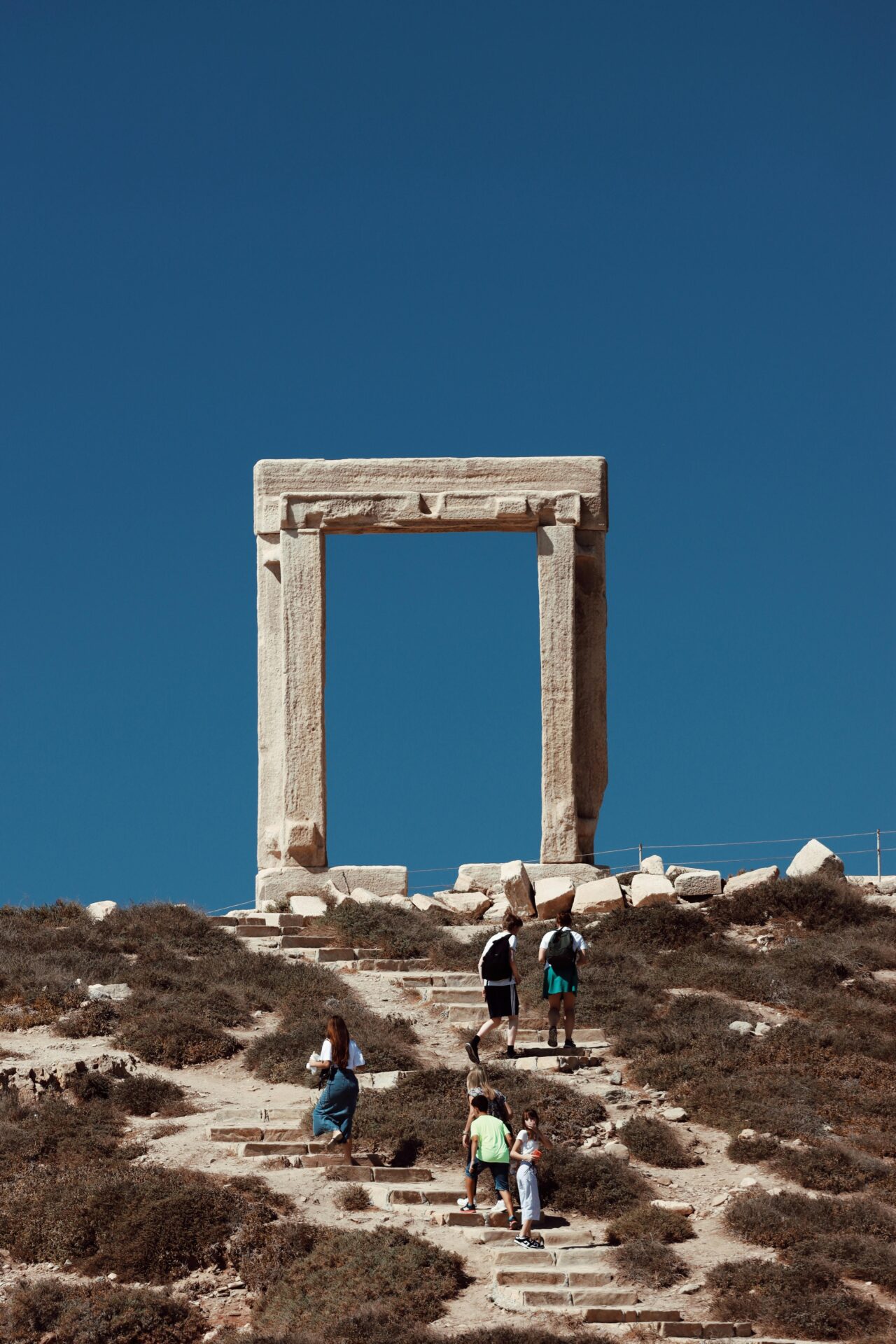 Ruins of the Temple of Apollo on the island of Naxos, with the iconic Portara (marble doorway) framed by the setting sun.