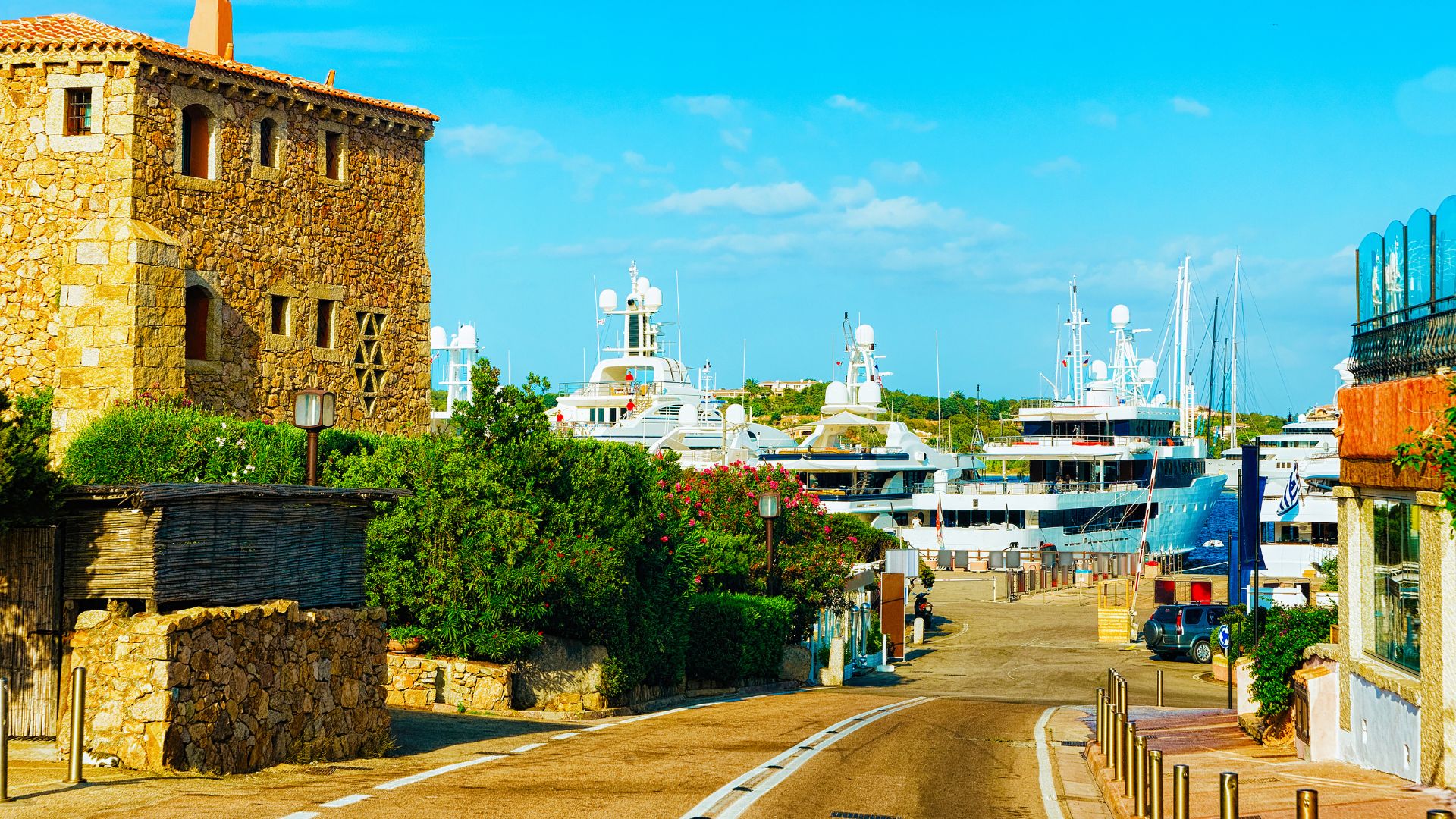 Street view in Porto Cervo, Sardinia, with stone buildings and yachts in the harbor