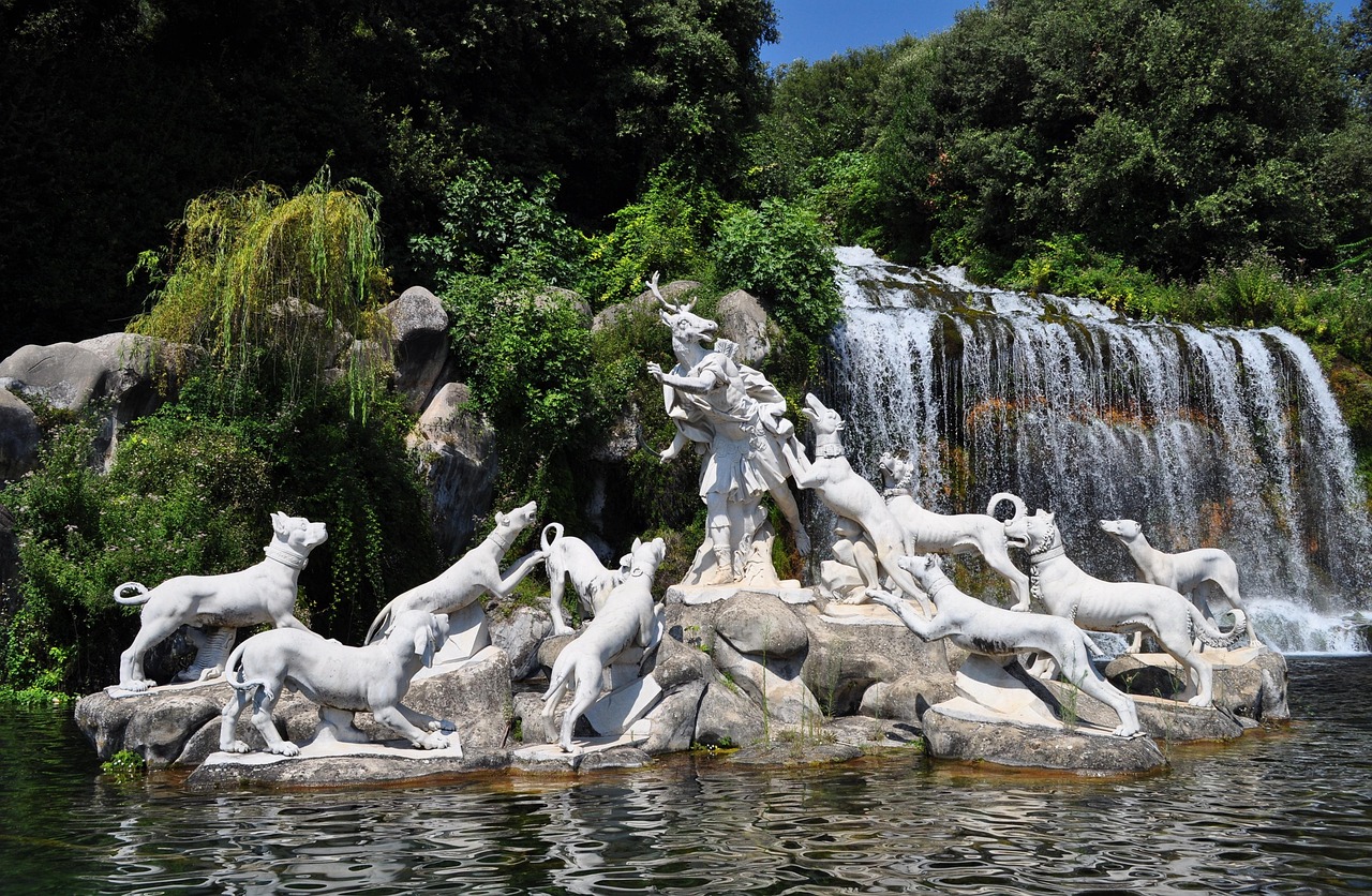 Marble statues of Diana and hunting dogs in front of a waterfall at the Royal Palace of Caserta’s gardens.
