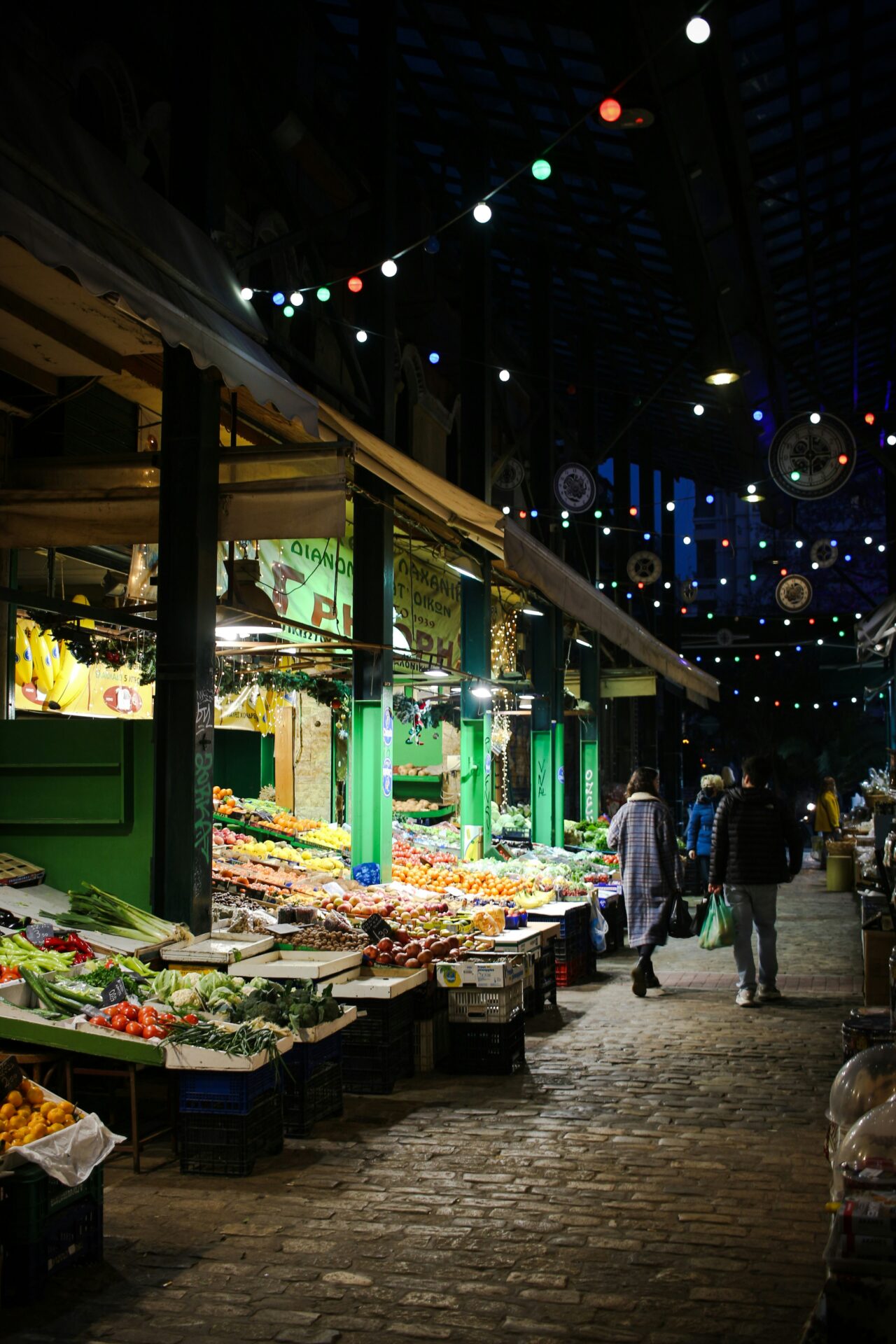 Locals and tourists browsing vibrant stalls in a historic Thessaloniki market