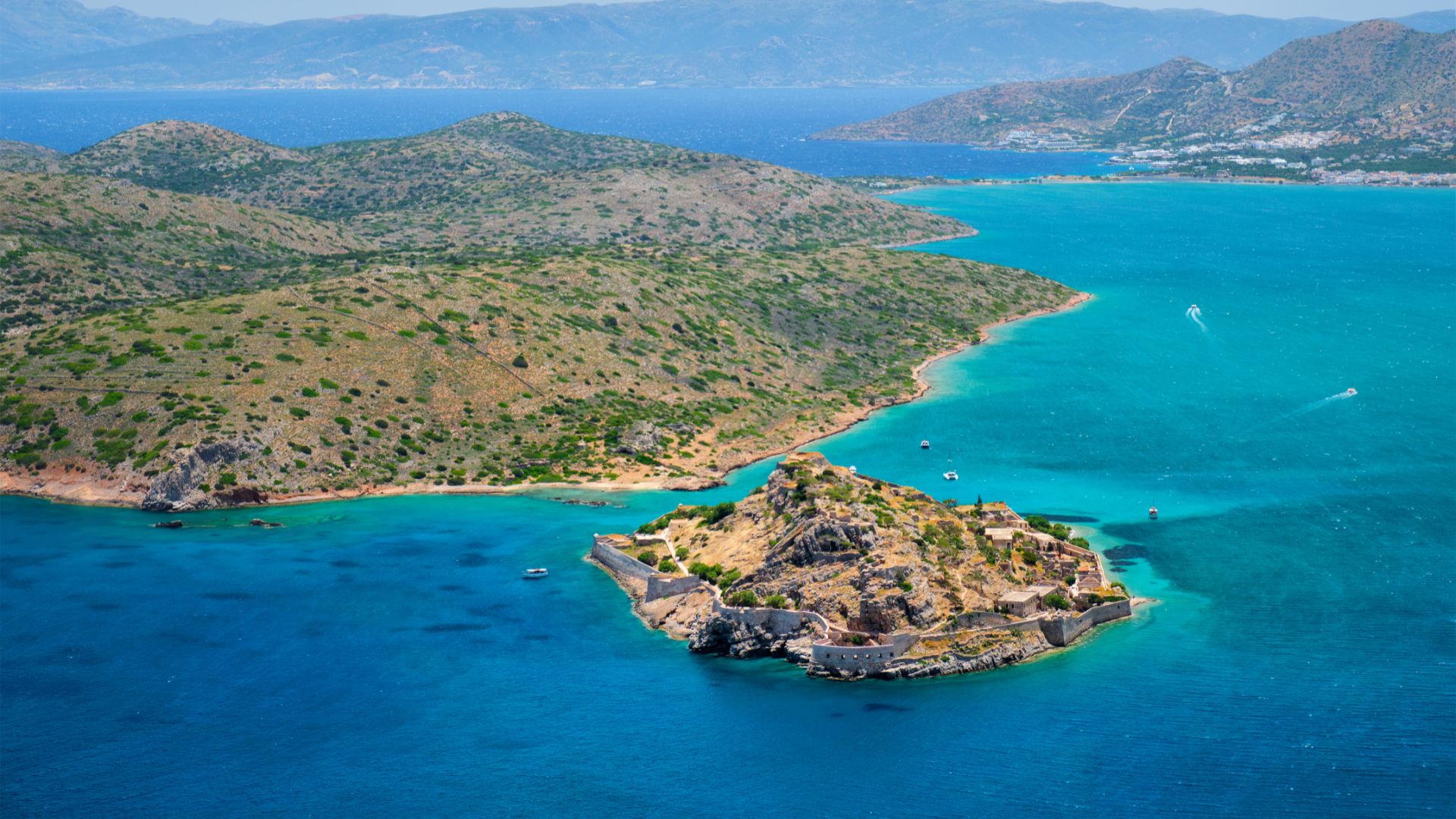Aerial view of Spinalonga Island, Crete, featuring the Venetian fortress ruins surrounded by turquoise waters.