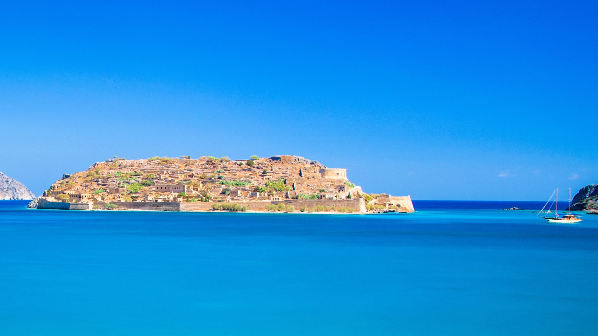 Spinalonga Island, Crete, featuring the Venetian fortress ruins surrounded by turquoise waters.