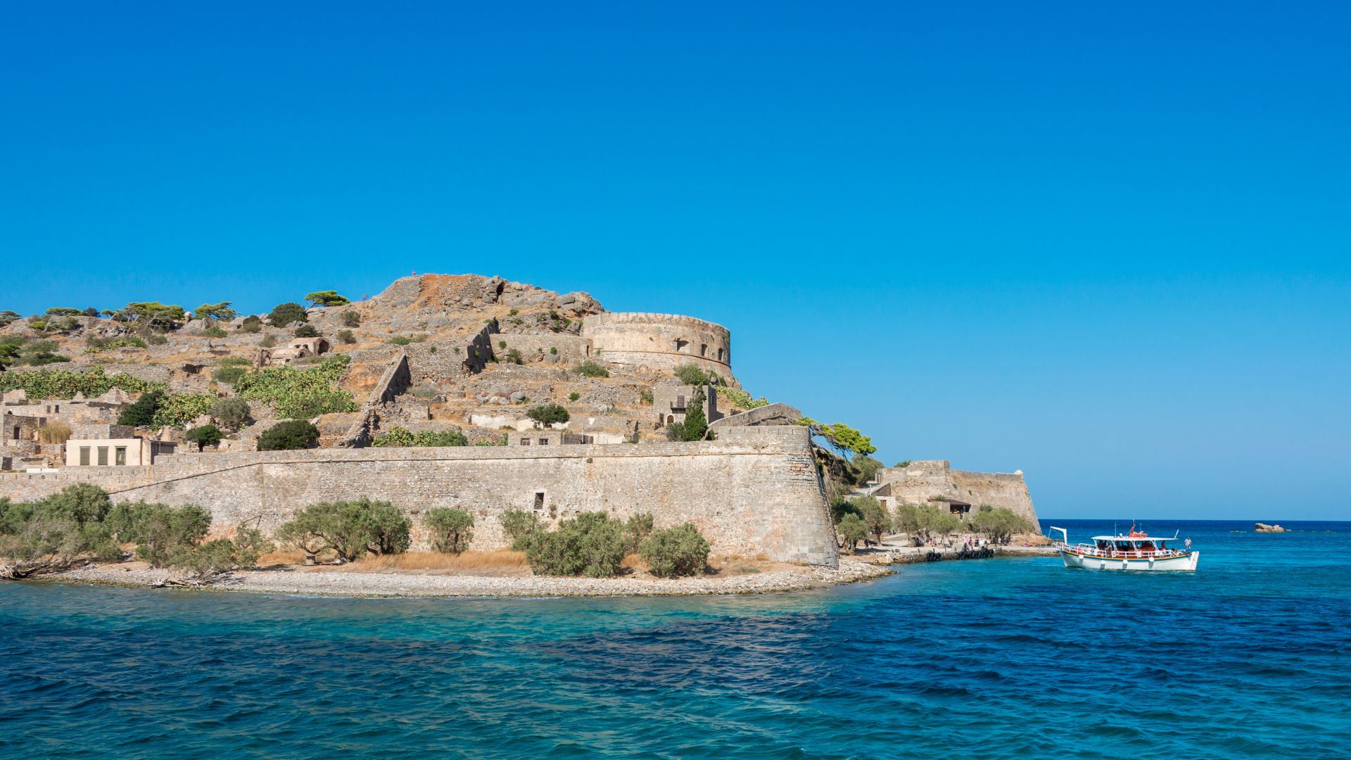 Spinalonga Island, Crete, featuring the Venetian fortress ruins surrounded by turquoise waters.