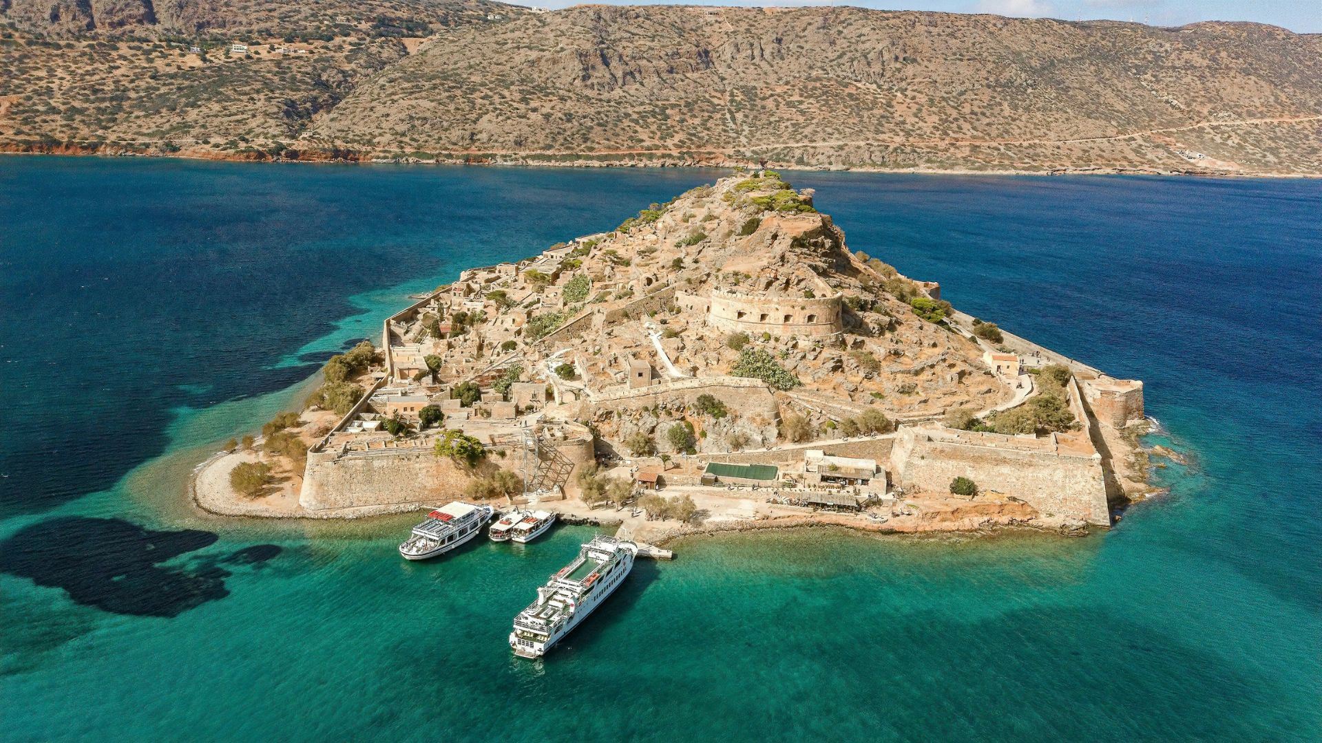 Spinalonga Island, Crete, featuring the Venetian fortress ruins surrounded by turquoise waters.