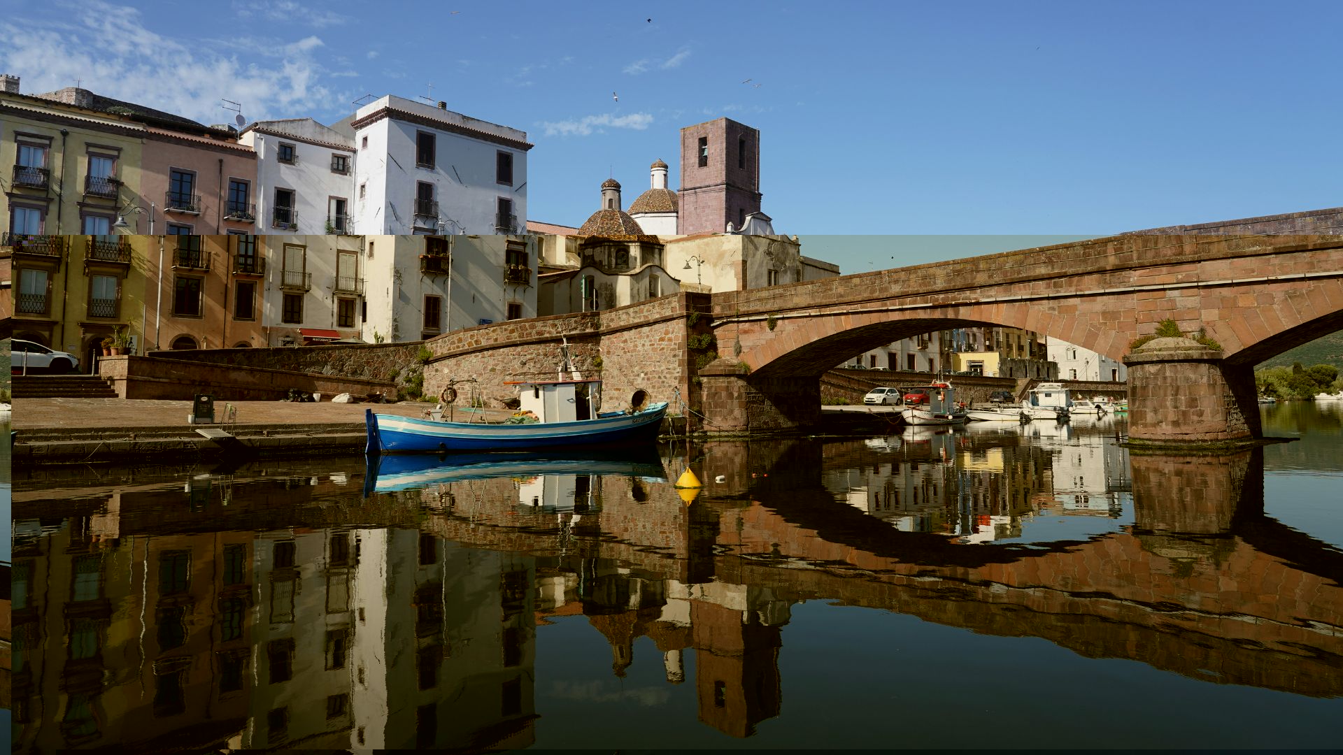 Bosa, Sardinia, with colorful buildings along the Temo River and a stone bridge.
