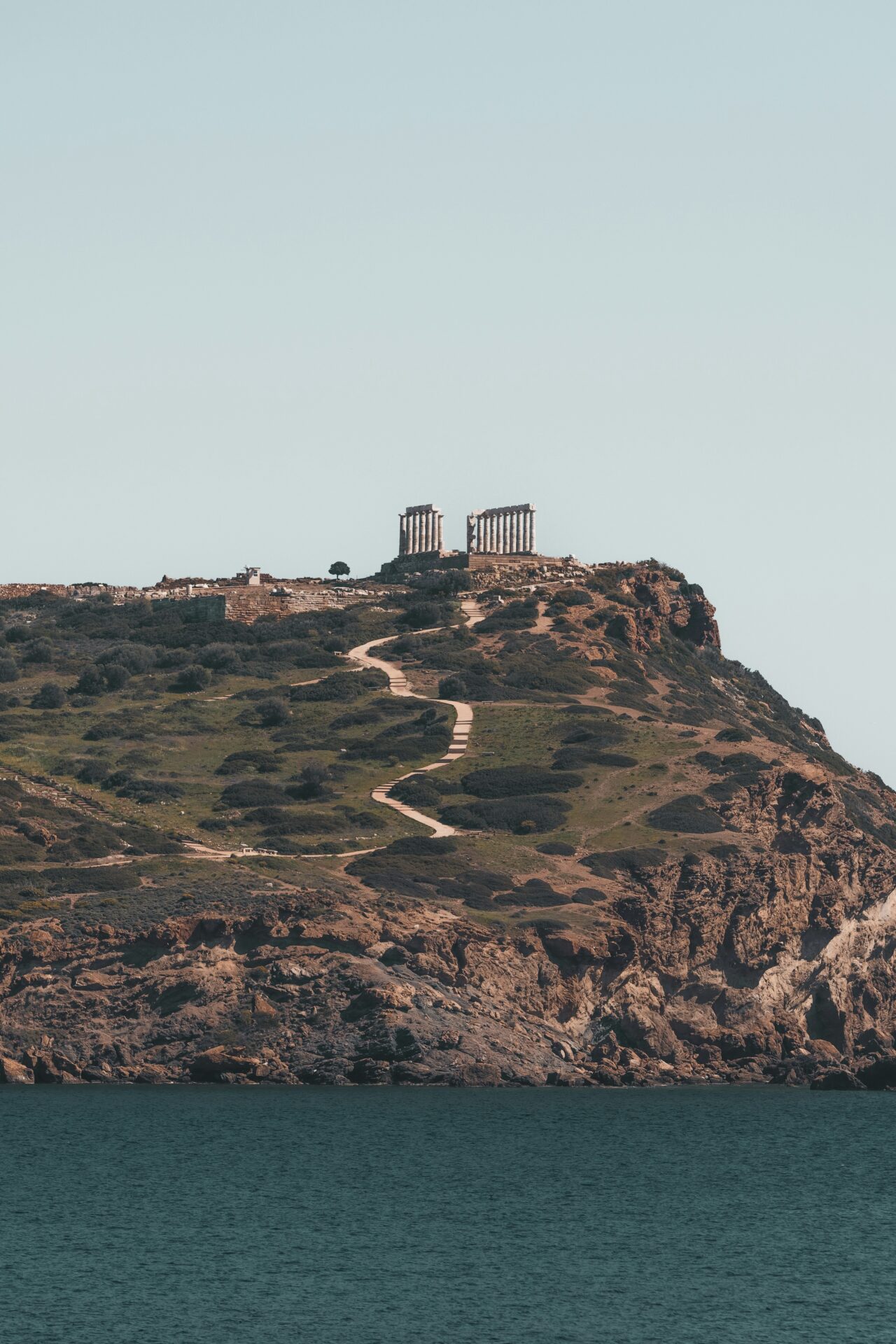 Distant view of the Temple of Poseidon on a cliff.