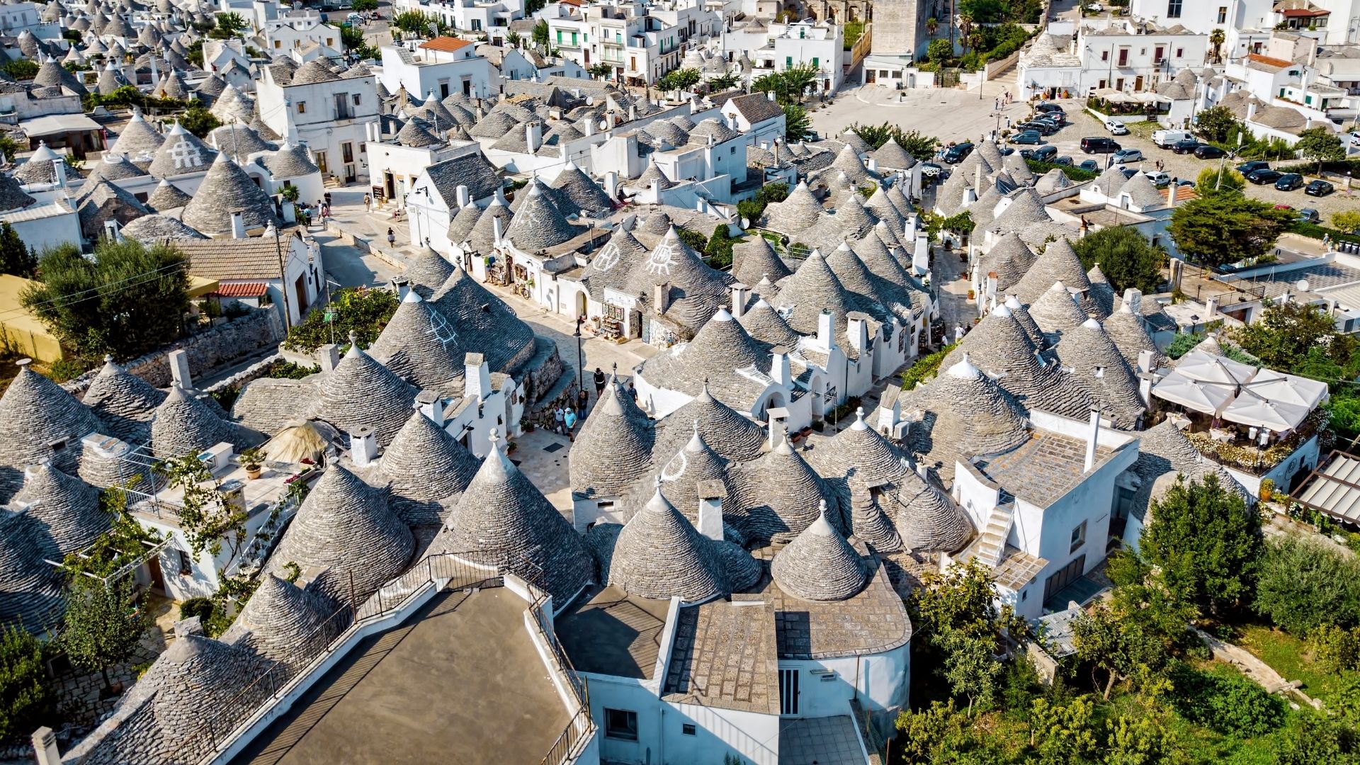 Aerial view of trulli houses in Alberobello, Italy, featuring their distinctive conical roofs and whitewashed walls.