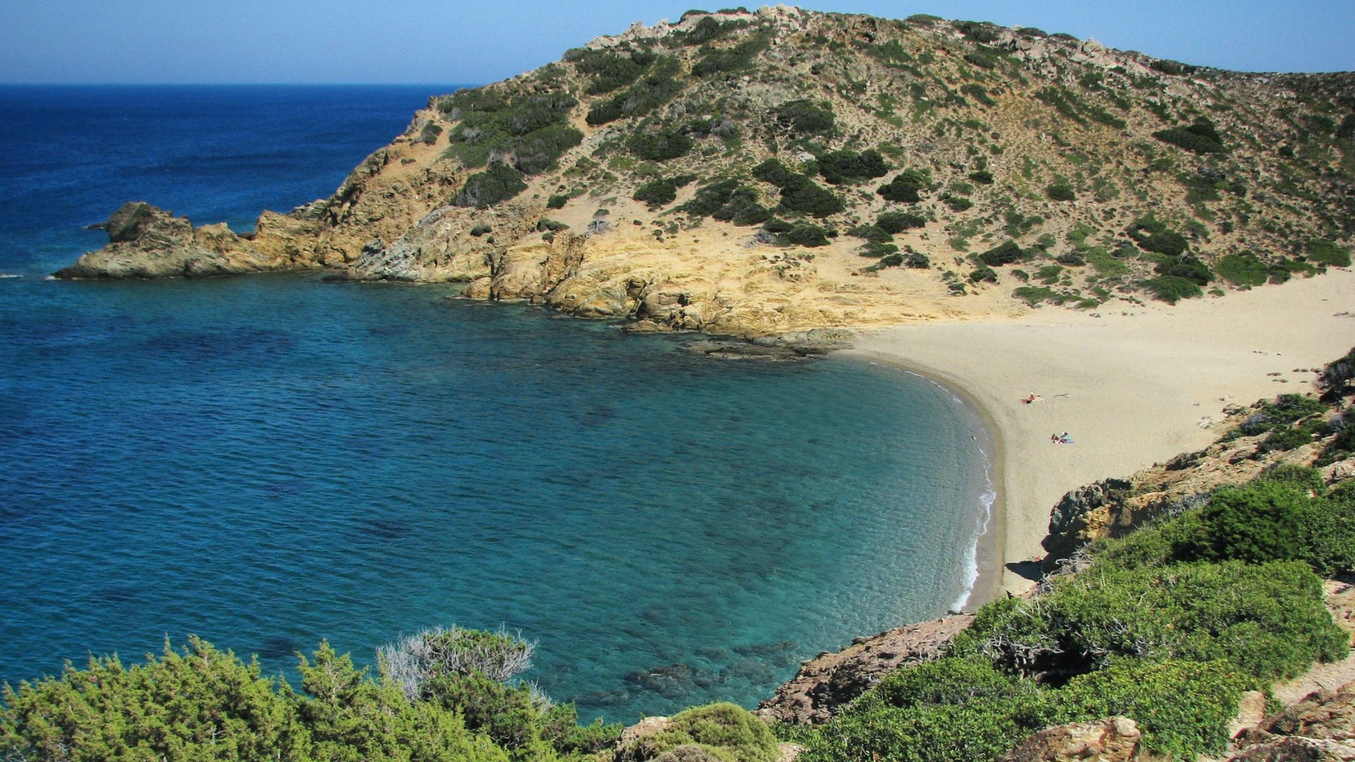 A scenic view of a beach with a rocky coastline and clear blue water.