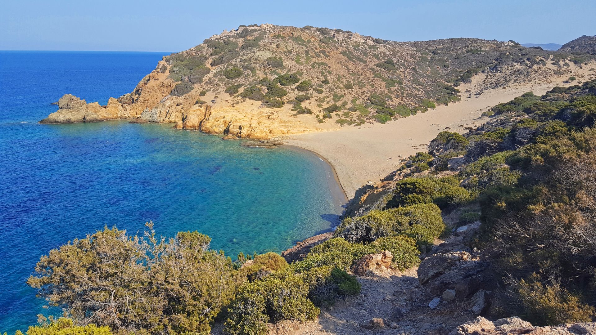 A scenic view of a beach with a rocky coastline and clear blue water.