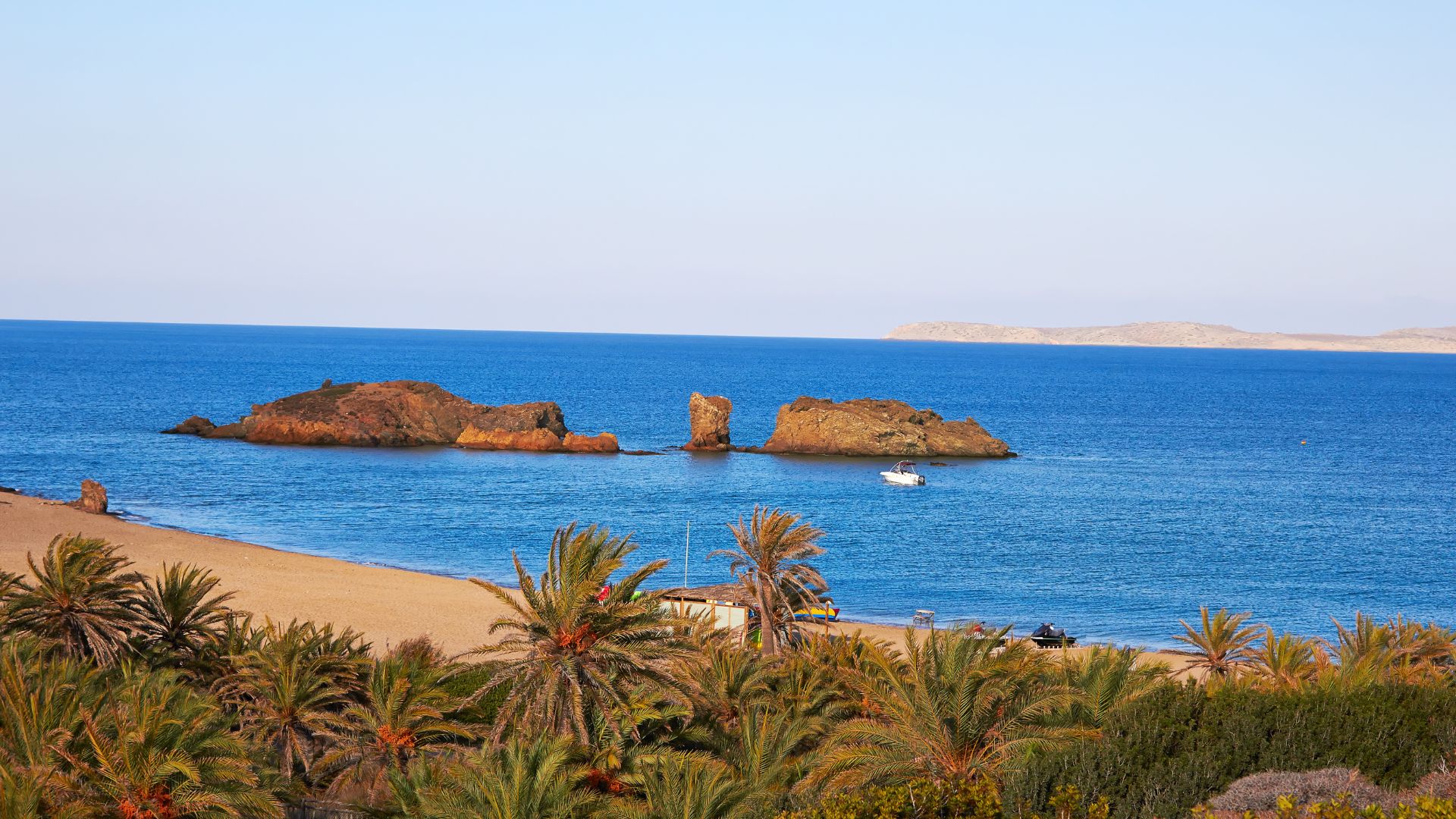 A scenic view of Vai Beach in Crete with palm trees and rocky islands.