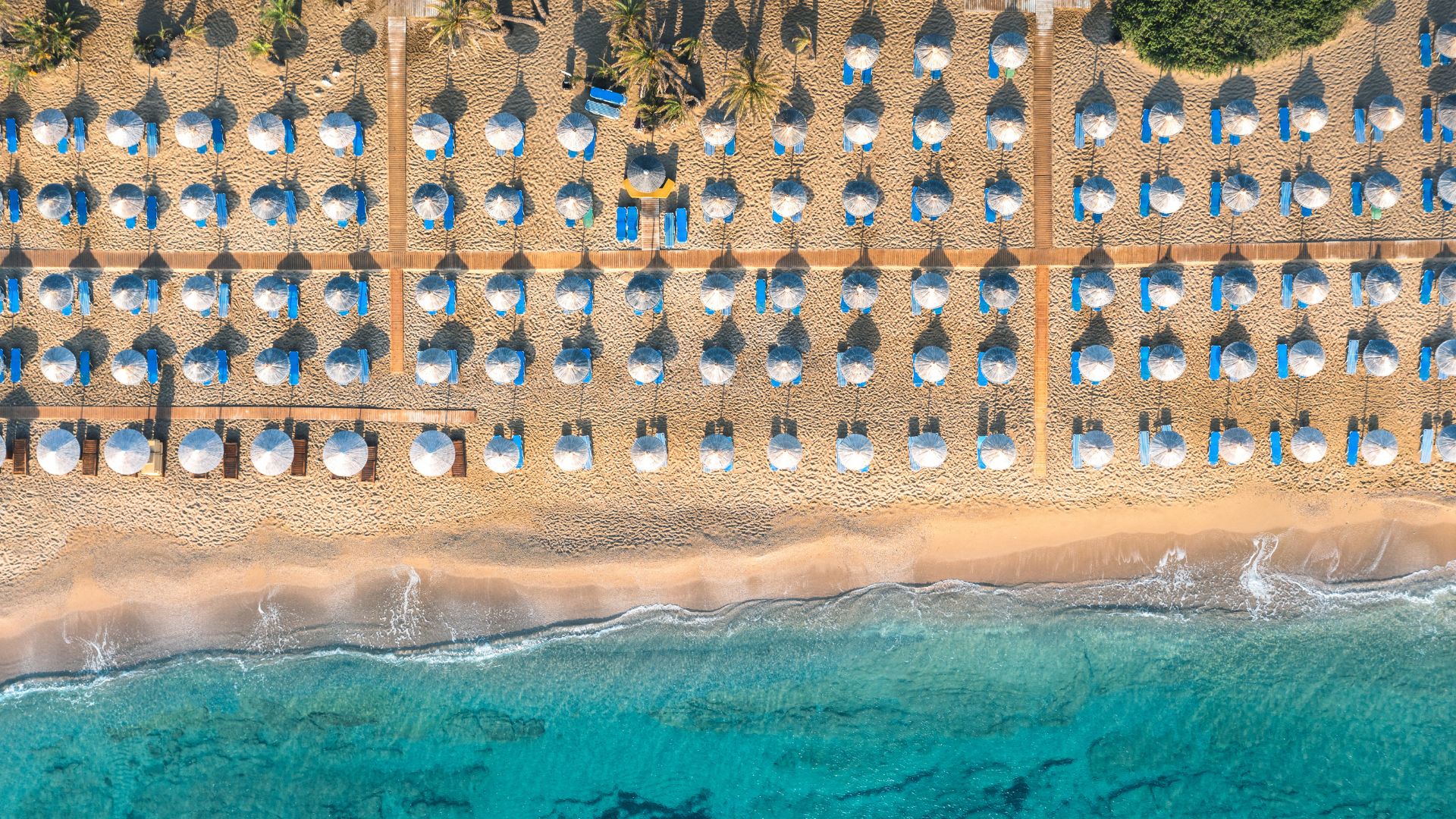 Aerial view of Vai Beach with palm trees and beach umbrellas.