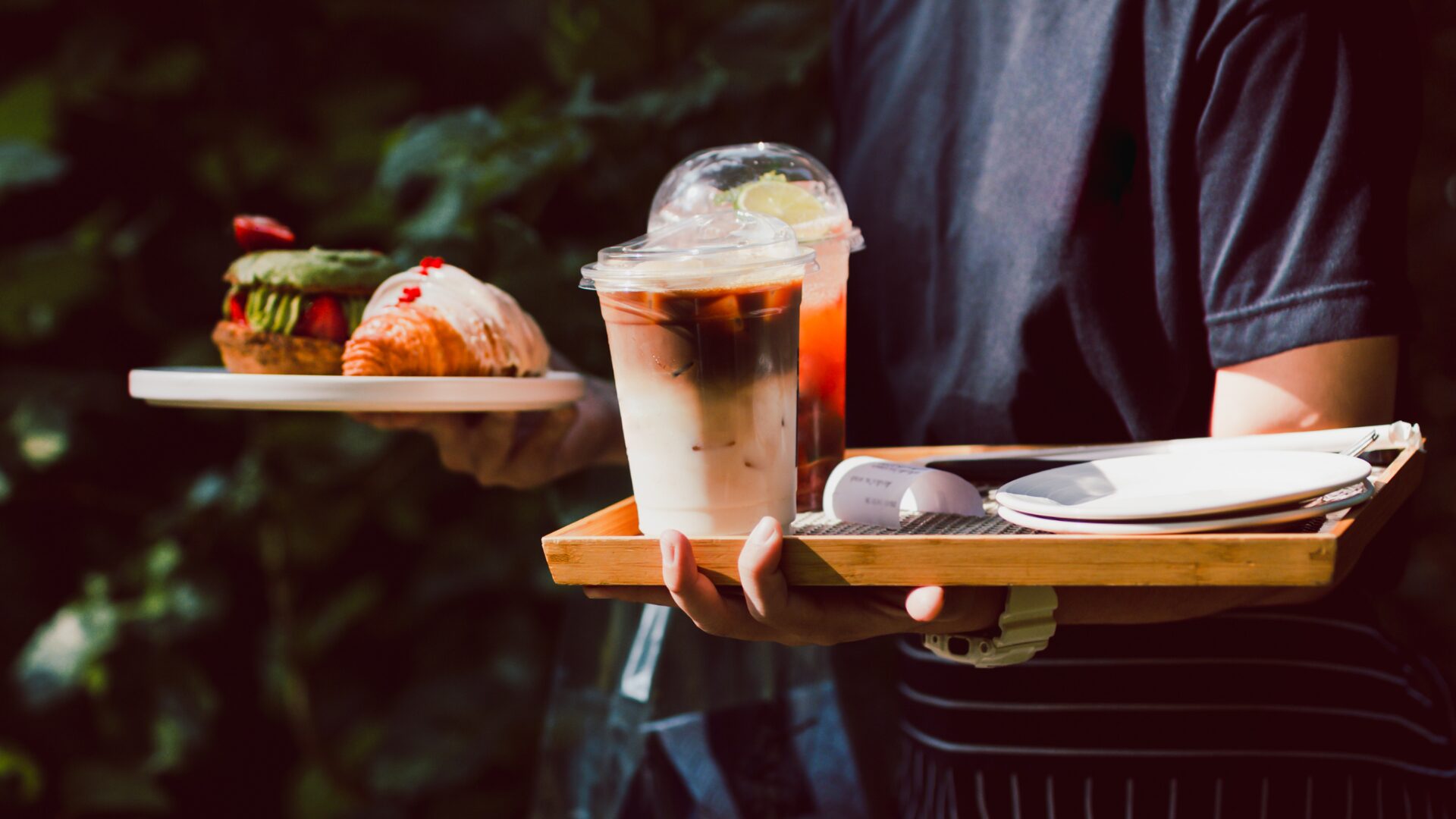 Waiter holding a tray with pastries and iced coffees