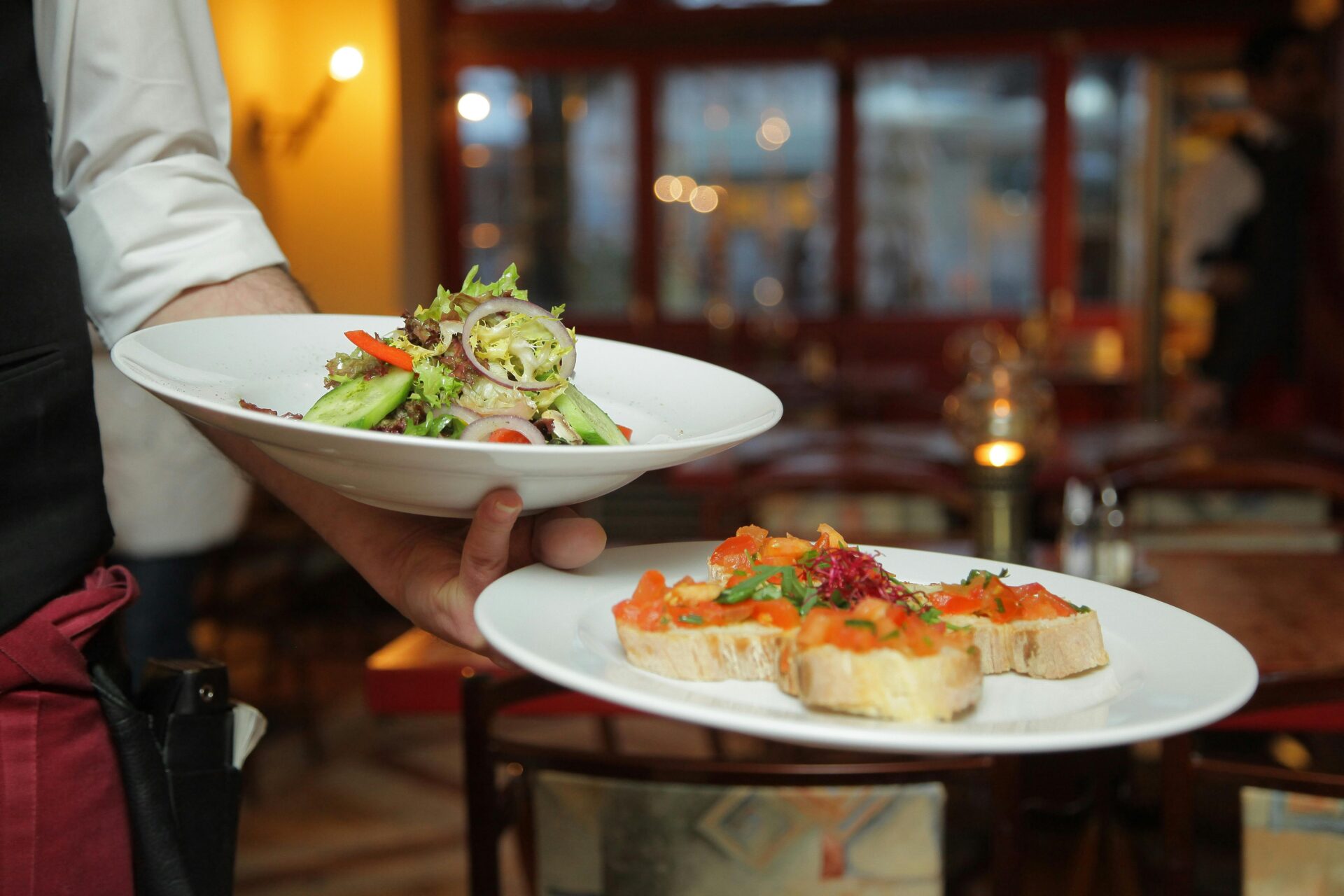 Waiter holding plates of bruschetta and salad