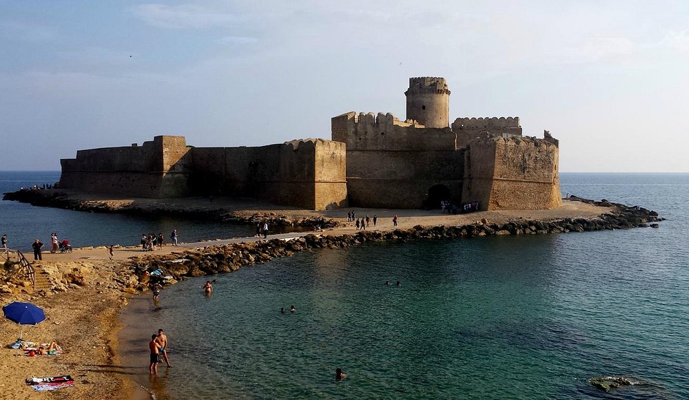 Aragonese castle with tourists swimming at the coast