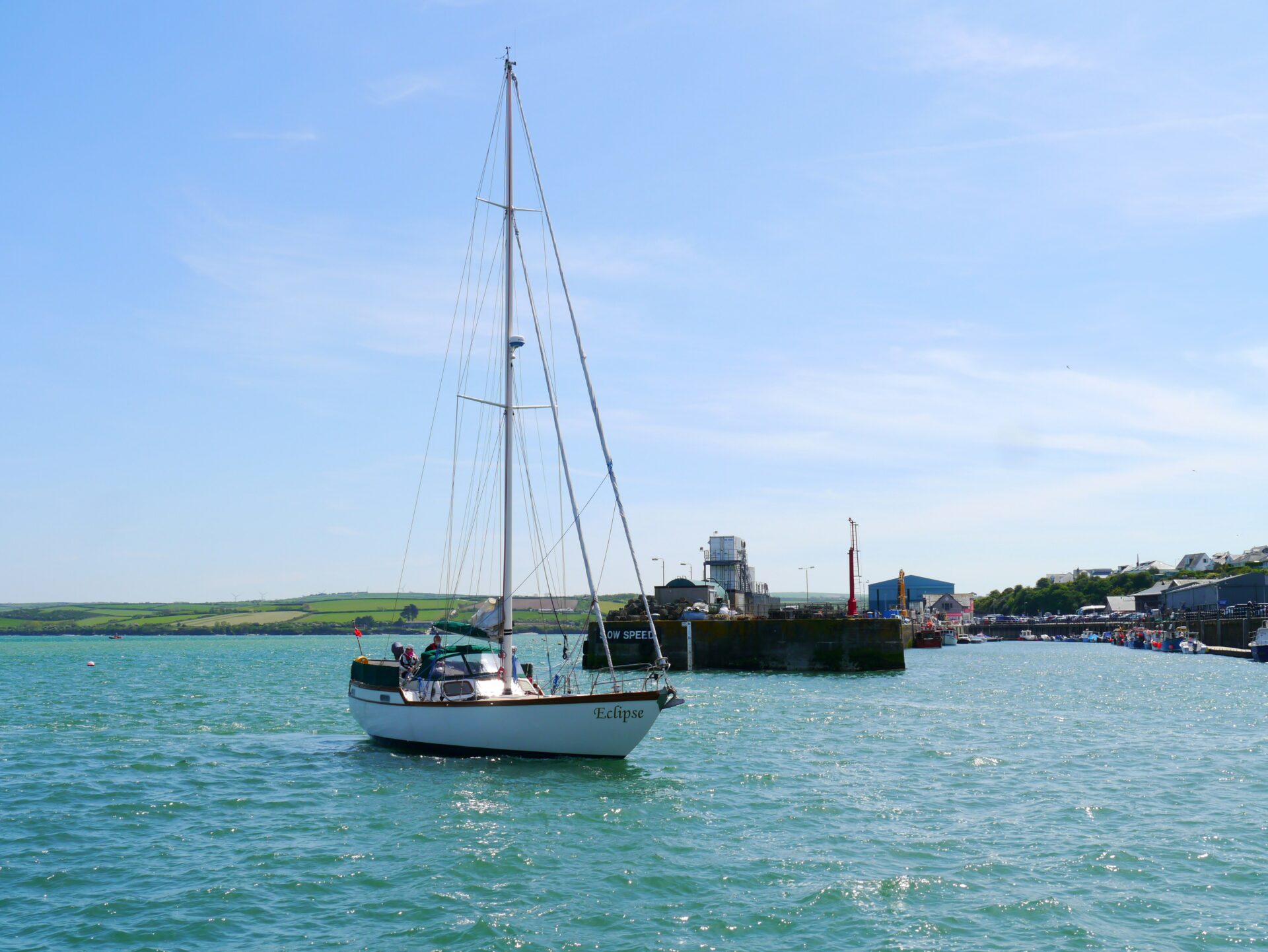 A sailboat gently gliding through the calm waters of Padstow harbor