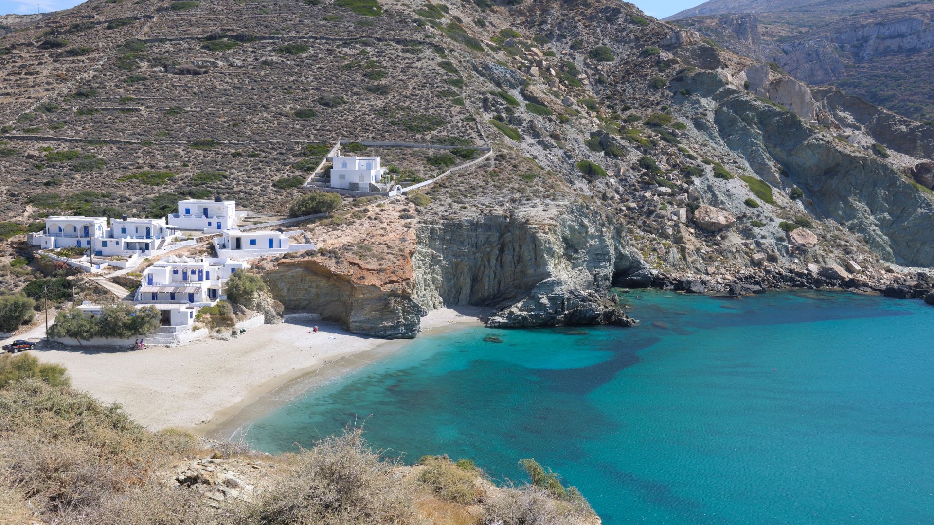 Agali Beach in Folegandros, Greece, featuring white buildings along a sandy cove.