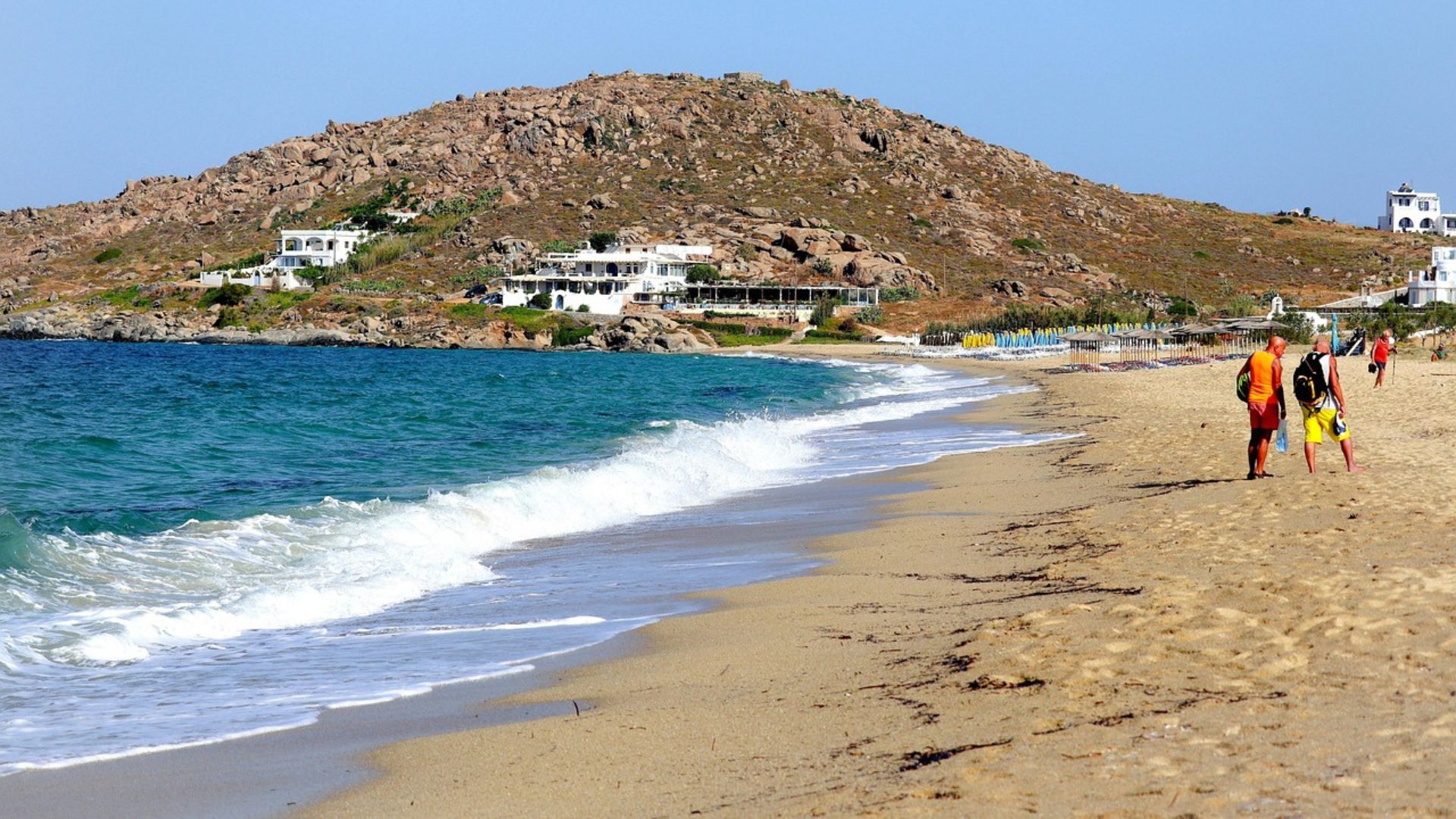 A sunny day at Agios Prokopios Beach with a rocky hill in the background.