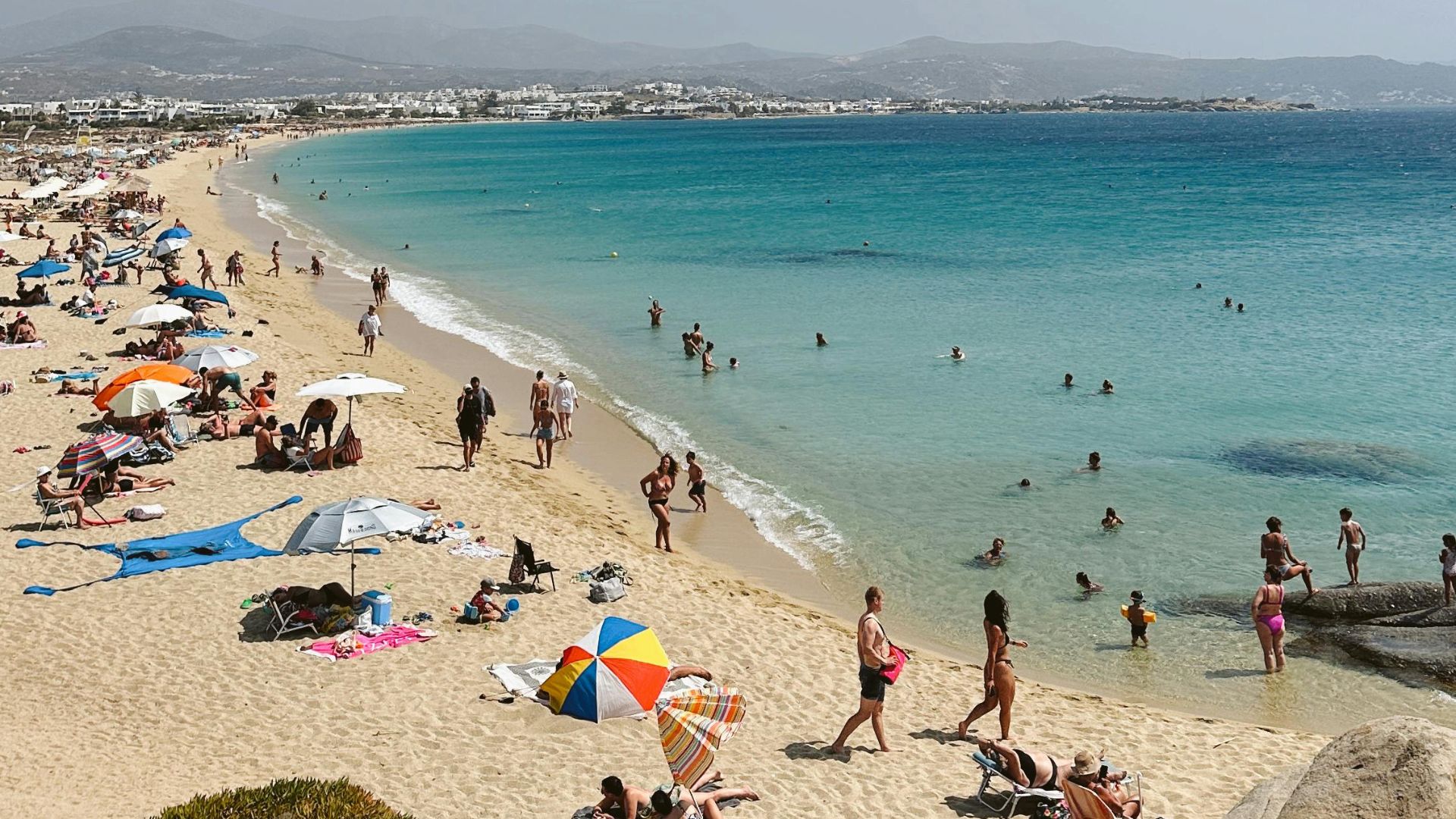 A sunny day at Agios Prokopios Beach with people enjoying the sand and sea.