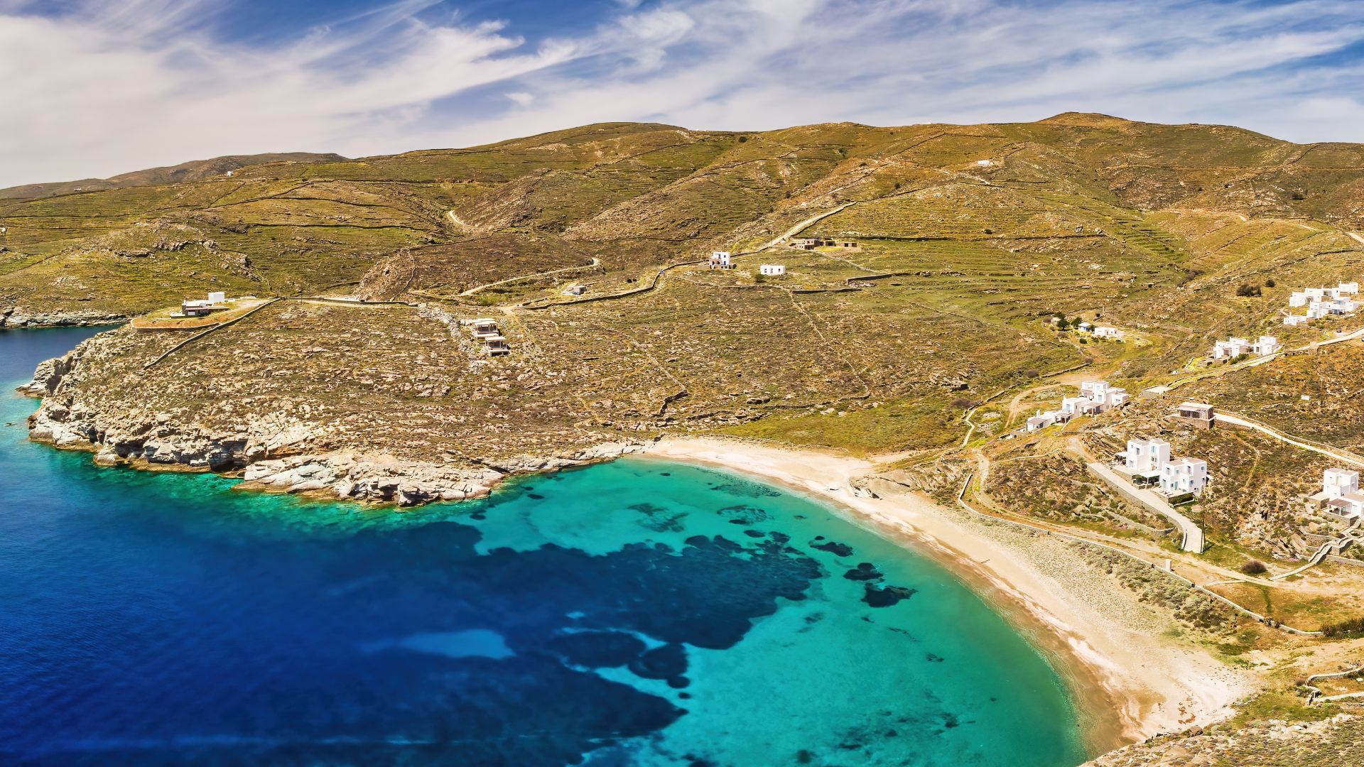 Agios Sostis Beach, Kythnos, Greece - panoramic view of a secluded sandy beach with turquoise waters and white buildings on a hillside