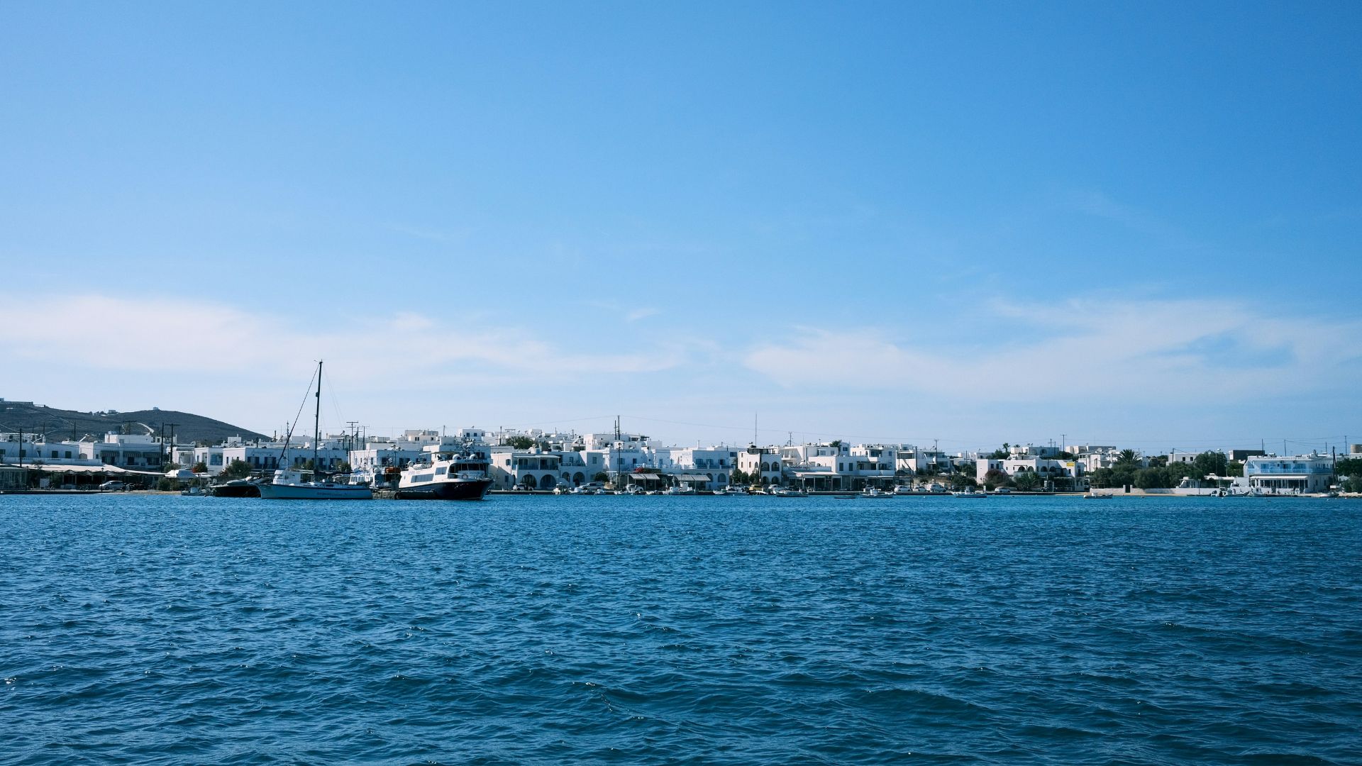 Antiparos Town waterfront, Greece, with whitewashed houses and boats on the Aegean Sea.