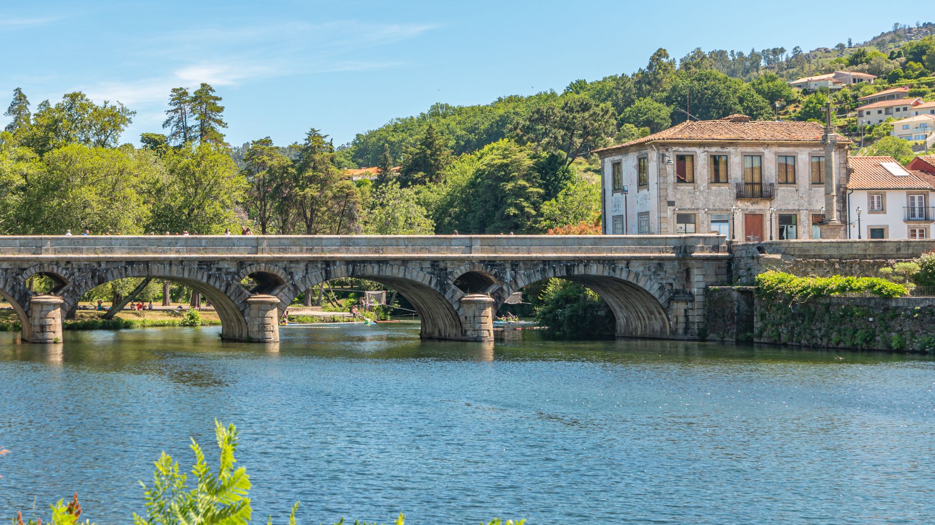 Stone bridge over the Vez River with a village on the bank, in Arcos de Valdevez, Portugal.