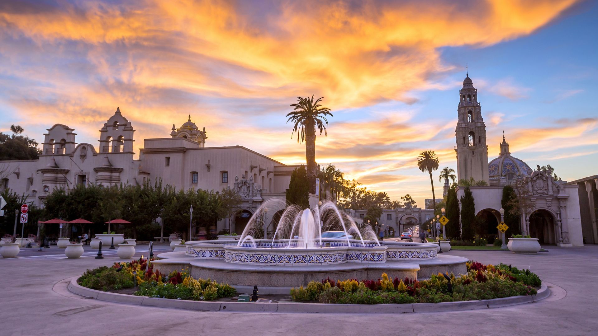 Stunning sunset over Balboa Park in San Diego, California, featuring the iconic Spreckels Organ Pavilion fountain, lush gardens, historic Spanish Colonial Revival architecture, and the California Tower.