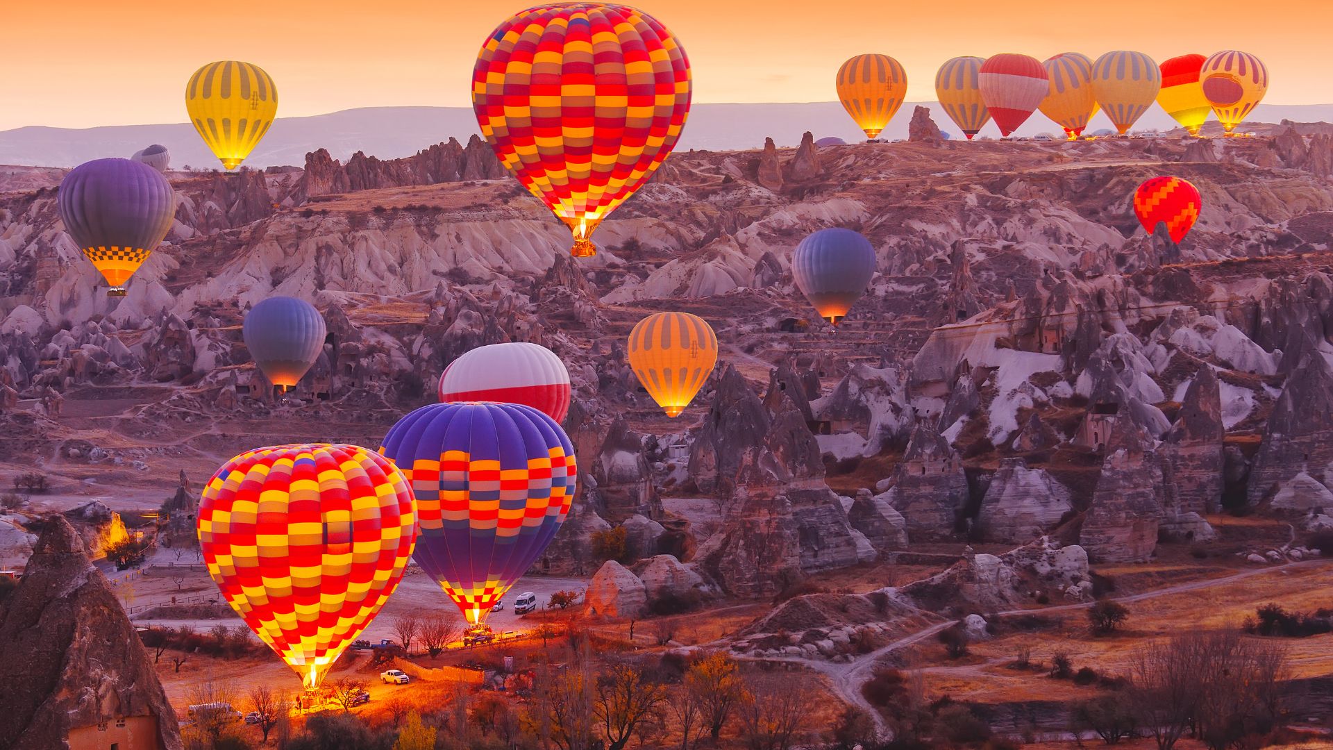 Cappadocia, Turkey at sunrise: A breathtaking landscape with numerous colorful hot air balloons floating over the unique rock formations and valleys.