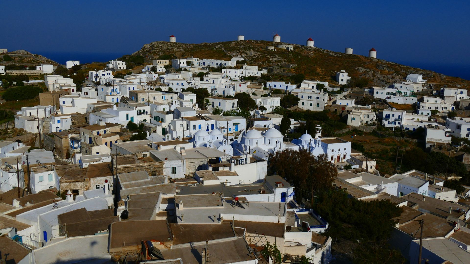 A hilltop village in Amorgos, Greece, featuring whitewashed houses and windmills.