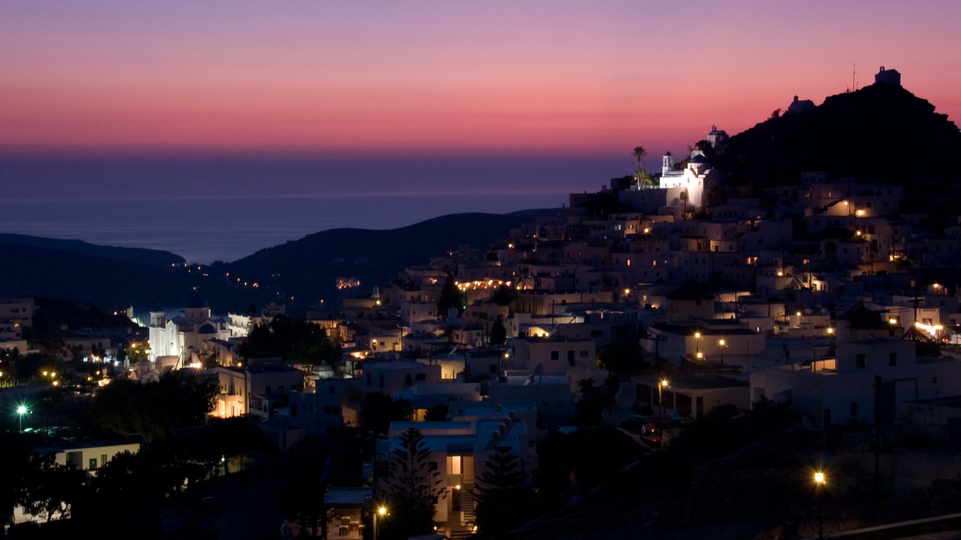 Chora, the main town of Ios, Greece with white buildings on a hill after sunset.