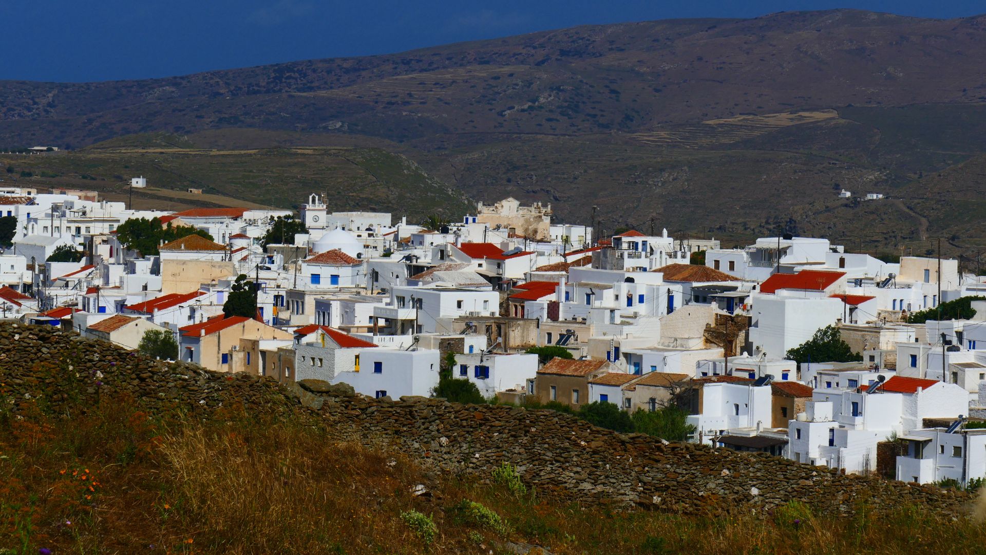 Whitewashed village of Chora, Kythnos Island, Greece, with traditional Cycladic architecture and red-tiled roofs nestled in a hilly landscape.