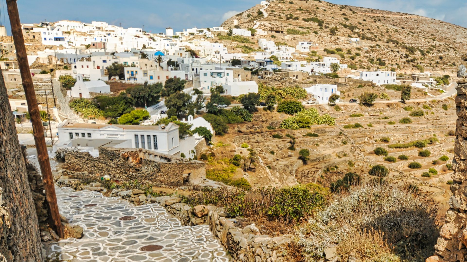 Traditional Cycladic village of Chora, Sikinos, Greece, featuring whitewashed buildings and stone pathways on a hillside.