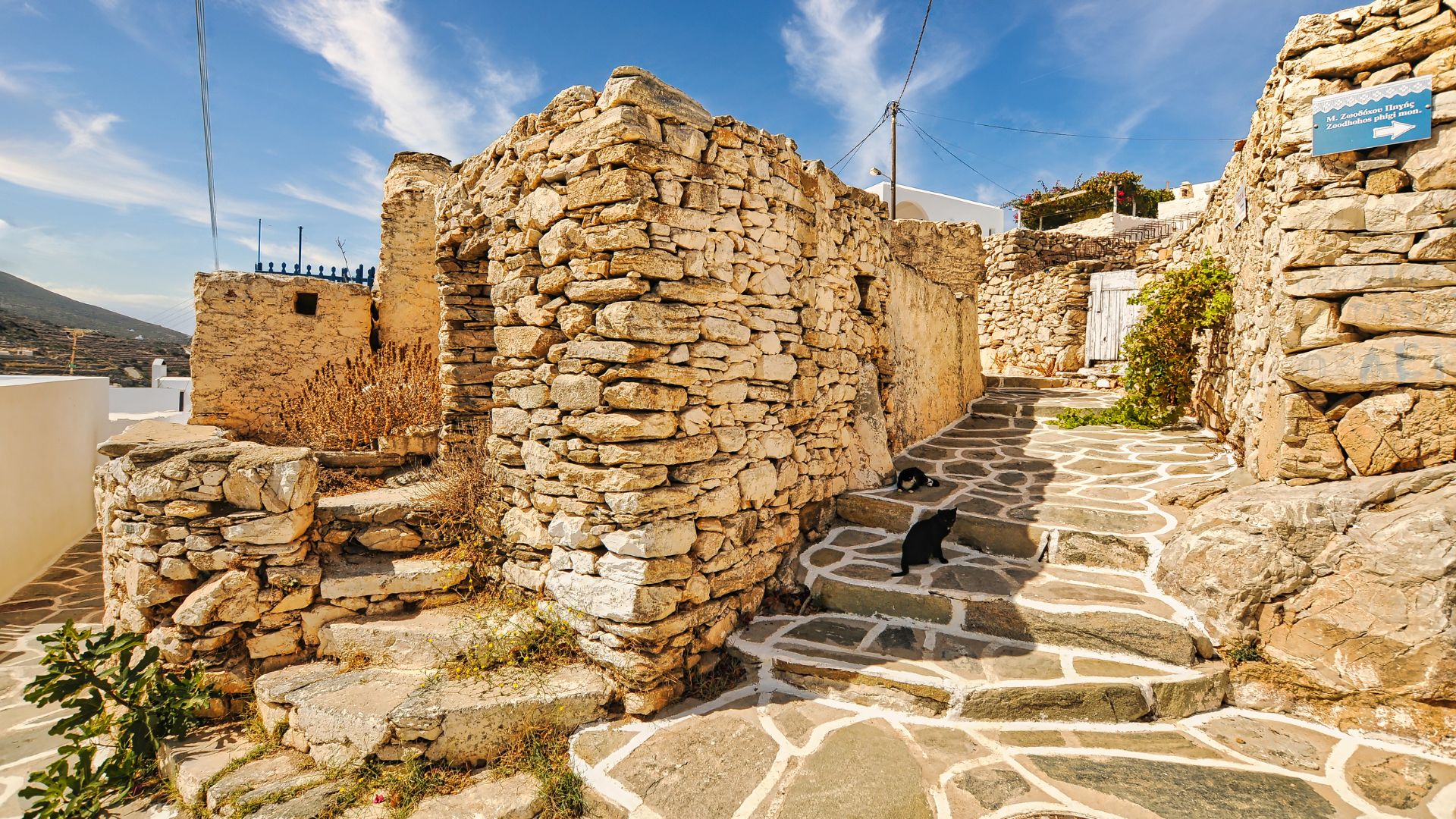 Cobblestone steps winding through stone houses in Kastro village, Sikinos, Greece.