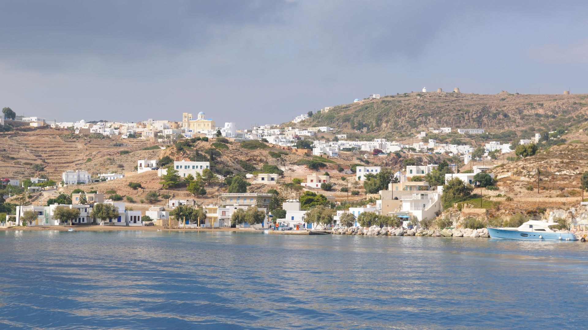 Kimolos Greece village coastline with traditional white houses and blue sea.