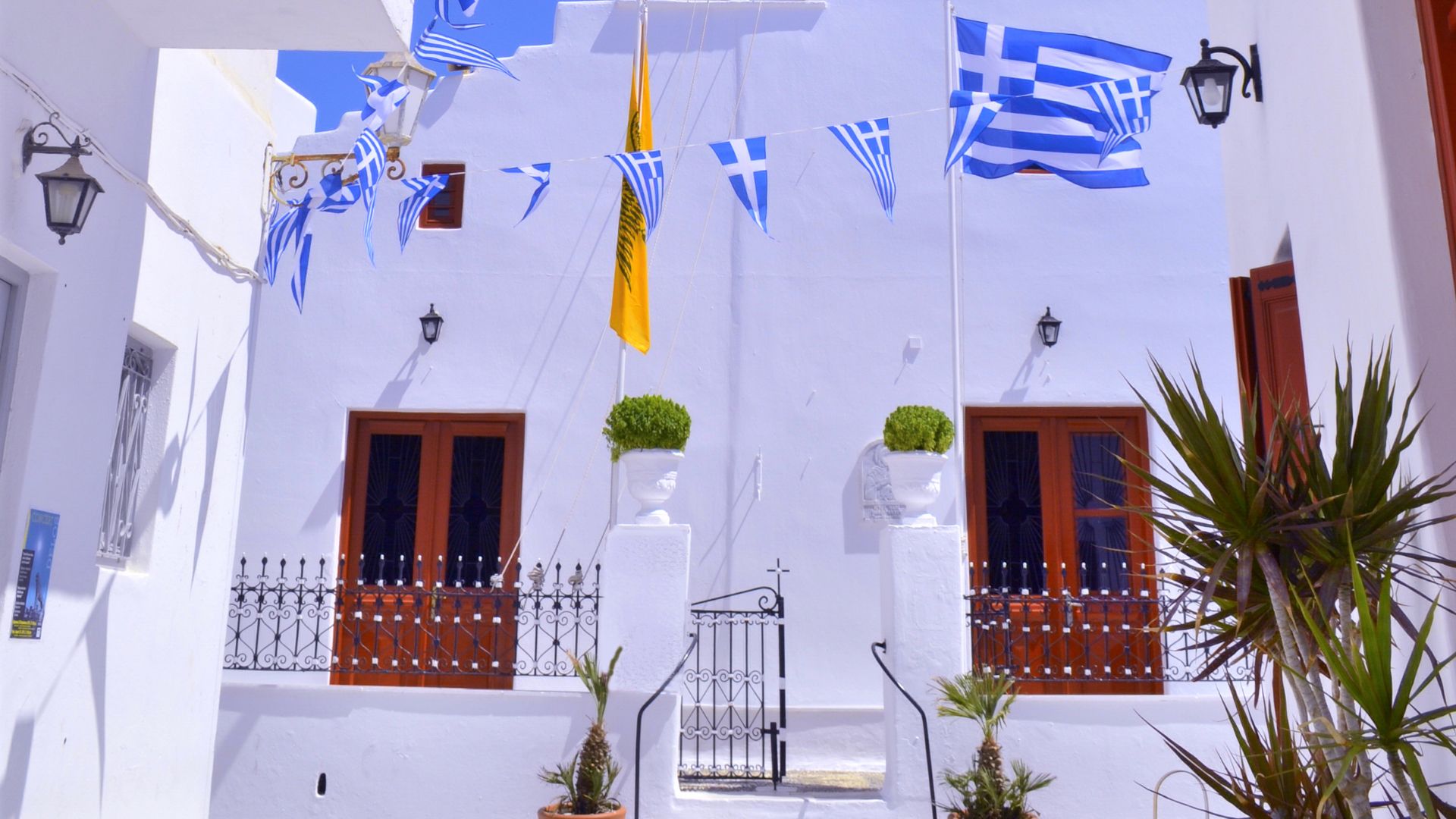 Church of Agios Kyriakos in Ano Mera, Mykonos, with Greek flags.