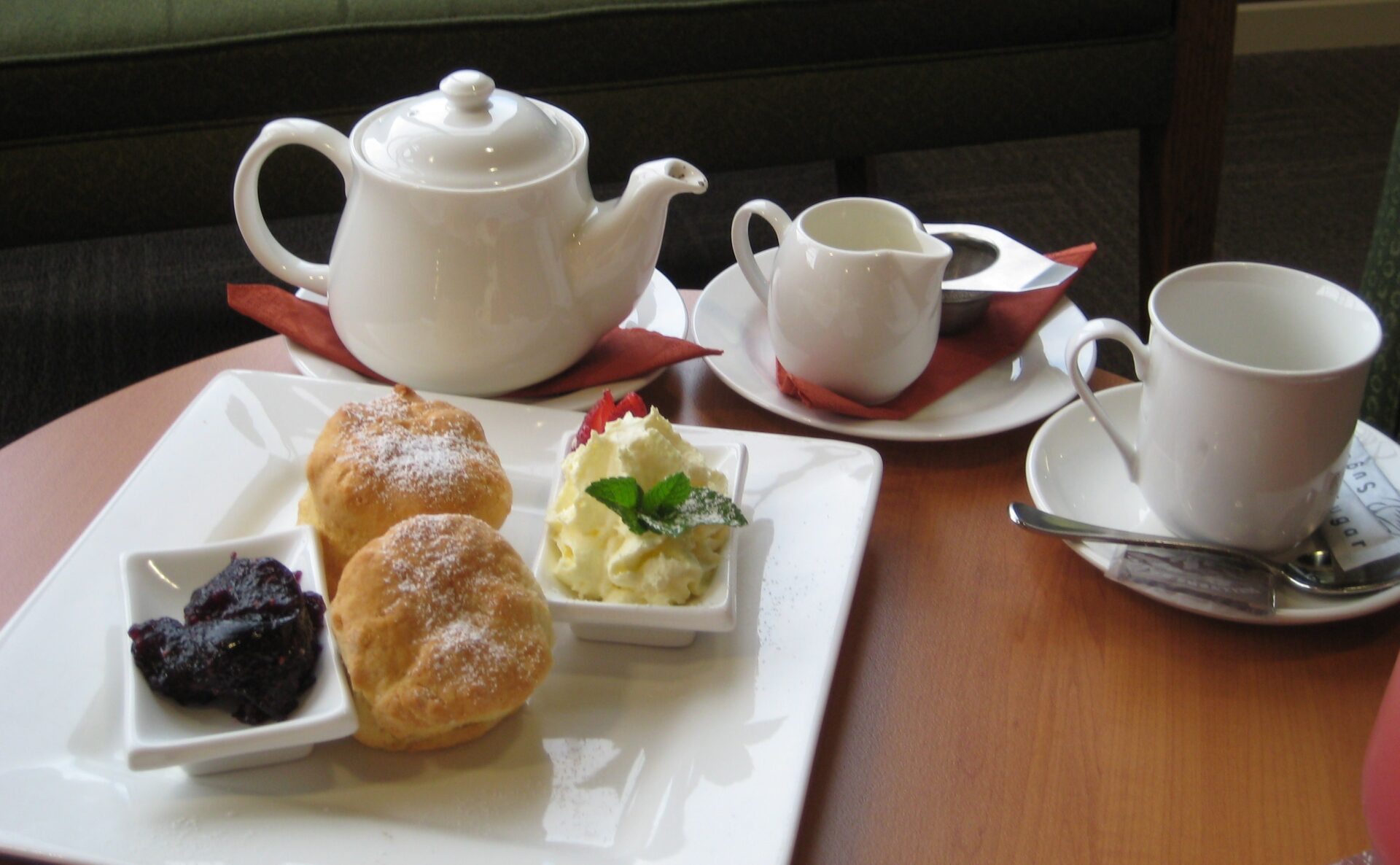 A traditional Cornish cream tea with scones, clotted cream, and strawberry jam, served with a pot of tea.