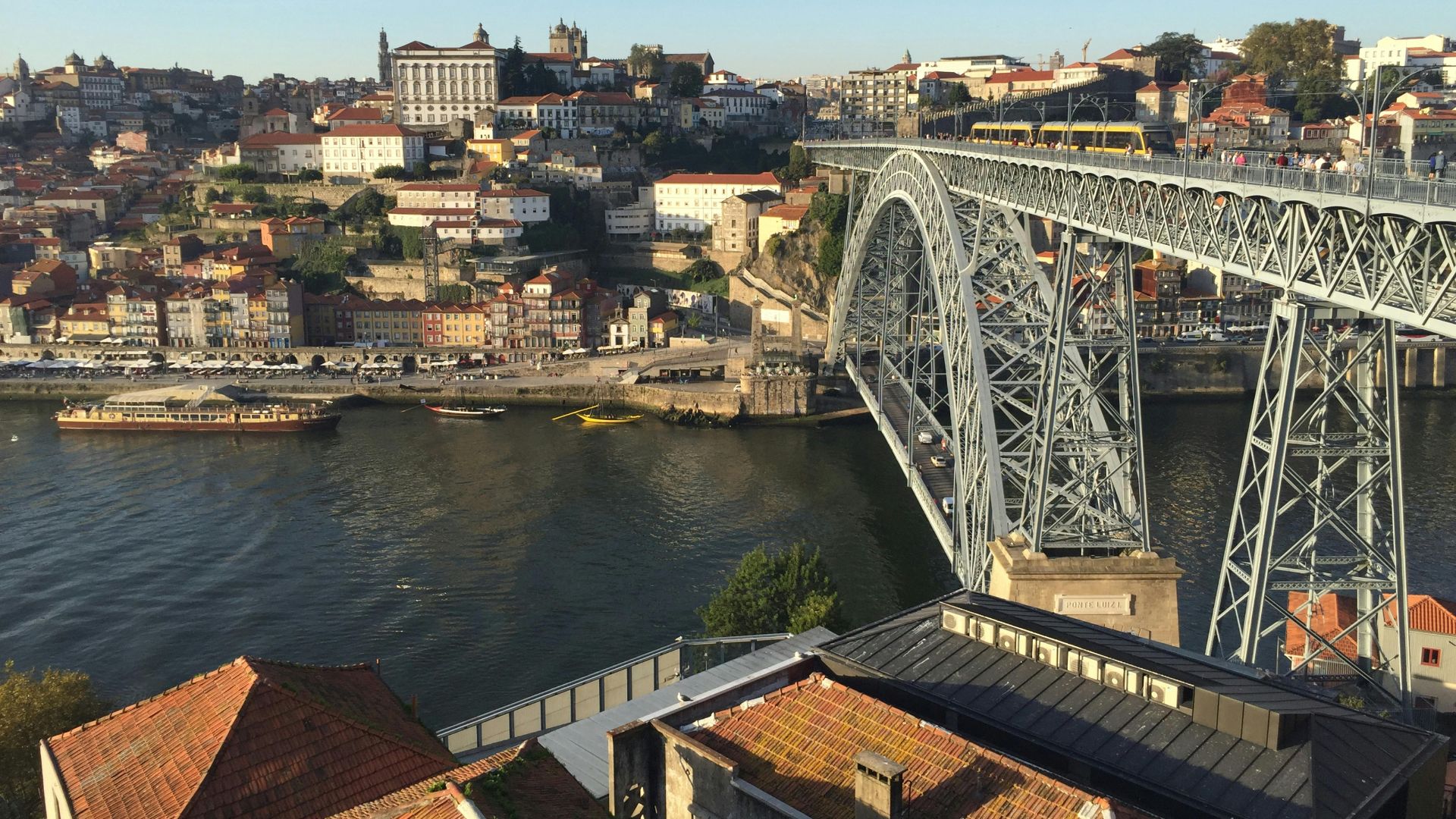Dom Luís I Bridge spanning the Douro River in Porto, Portugal, connecting Porto and Vila Nova de Gaia with boats docked along the riverbank.