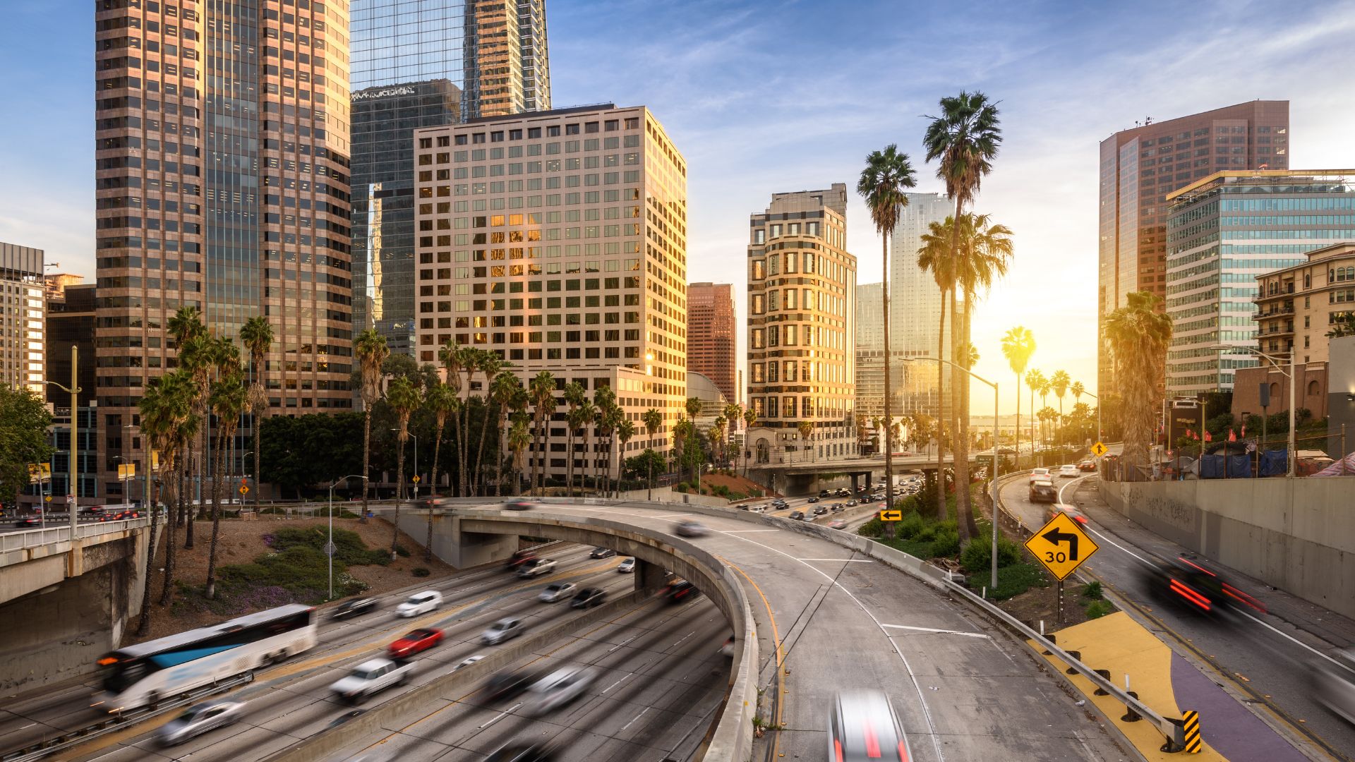 The image shows a multi-lane highway or freeway with several overpasses and tall buildings in the background