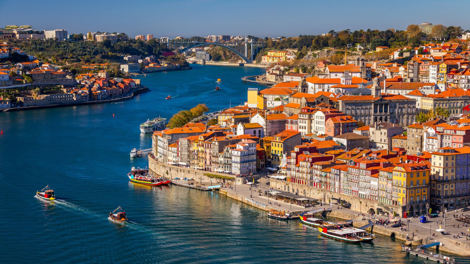 Aerial view of the colorful Ribeira district in Porto, Portugal, with historic buildings lining the Douro River and boats on the water.
